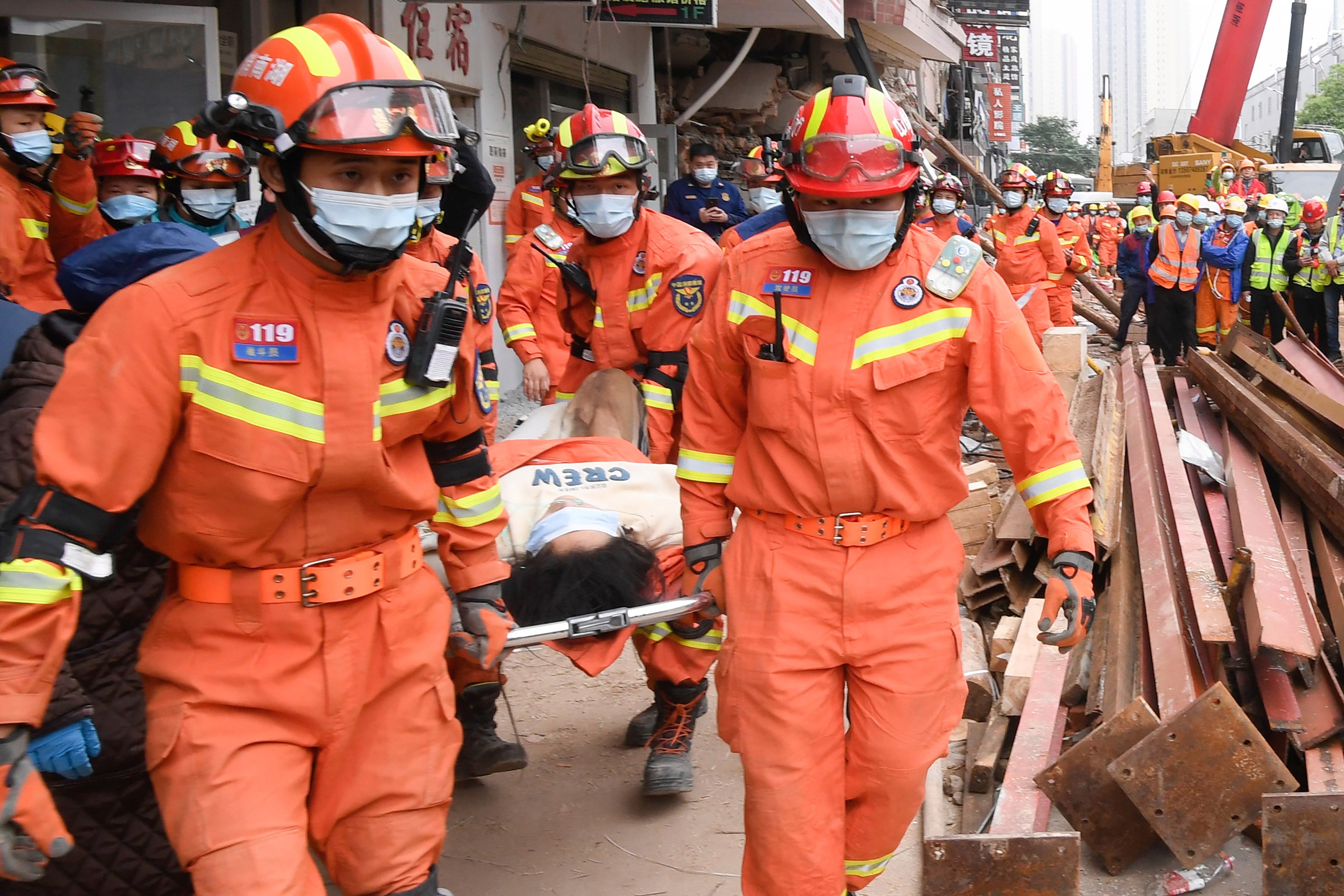 Rescuers evacuate a woman pulled alive from a collapsed building in Changsha, central China