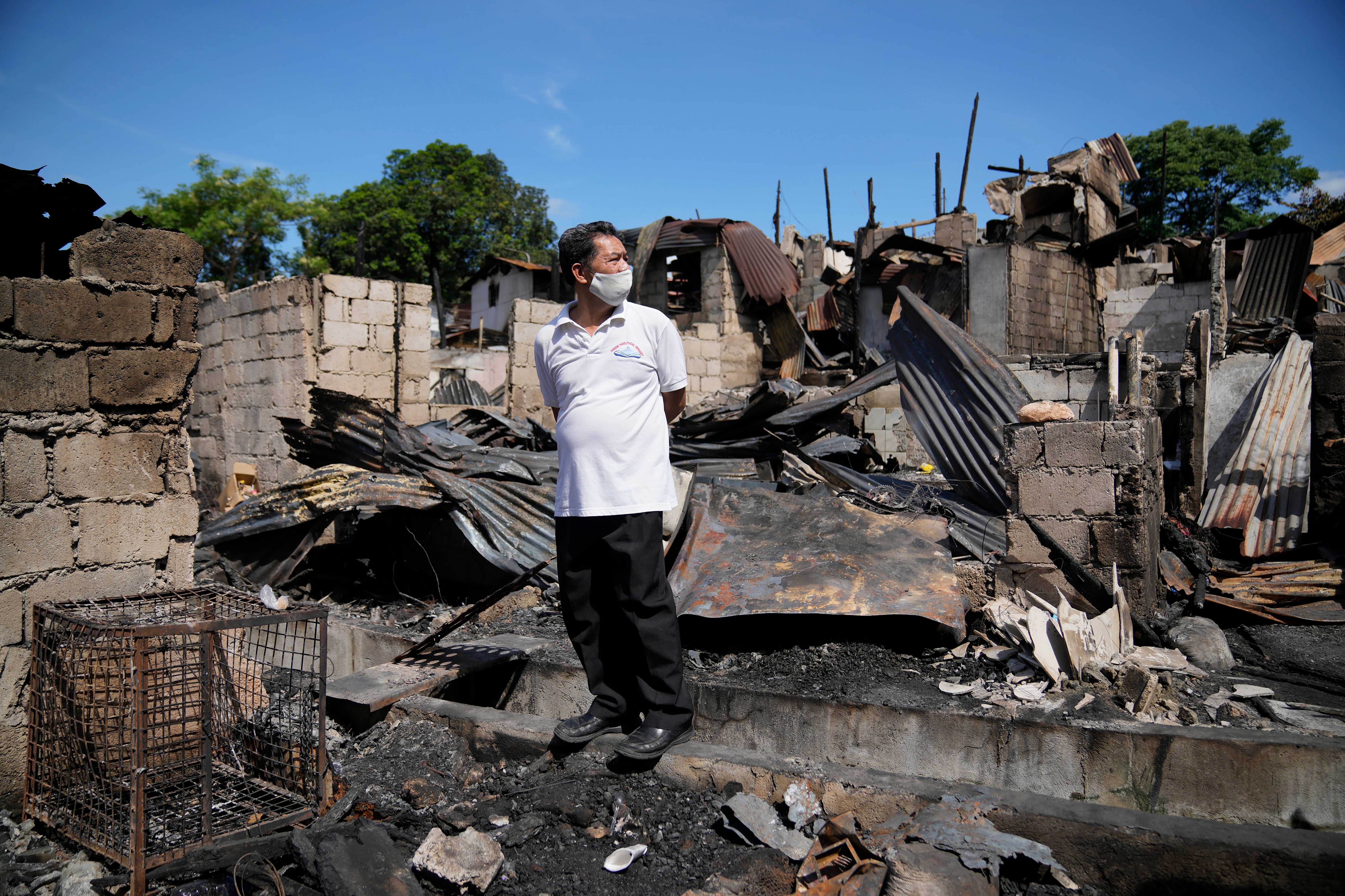 A man stands beside remains of homes after a fire gutted a residential area in Quezon city, Philippines on Monday