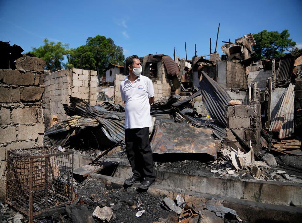 <p>A man stands beside remains of homes after a fire gutted a residential area in Quezon city, Philippines on Monday</p>