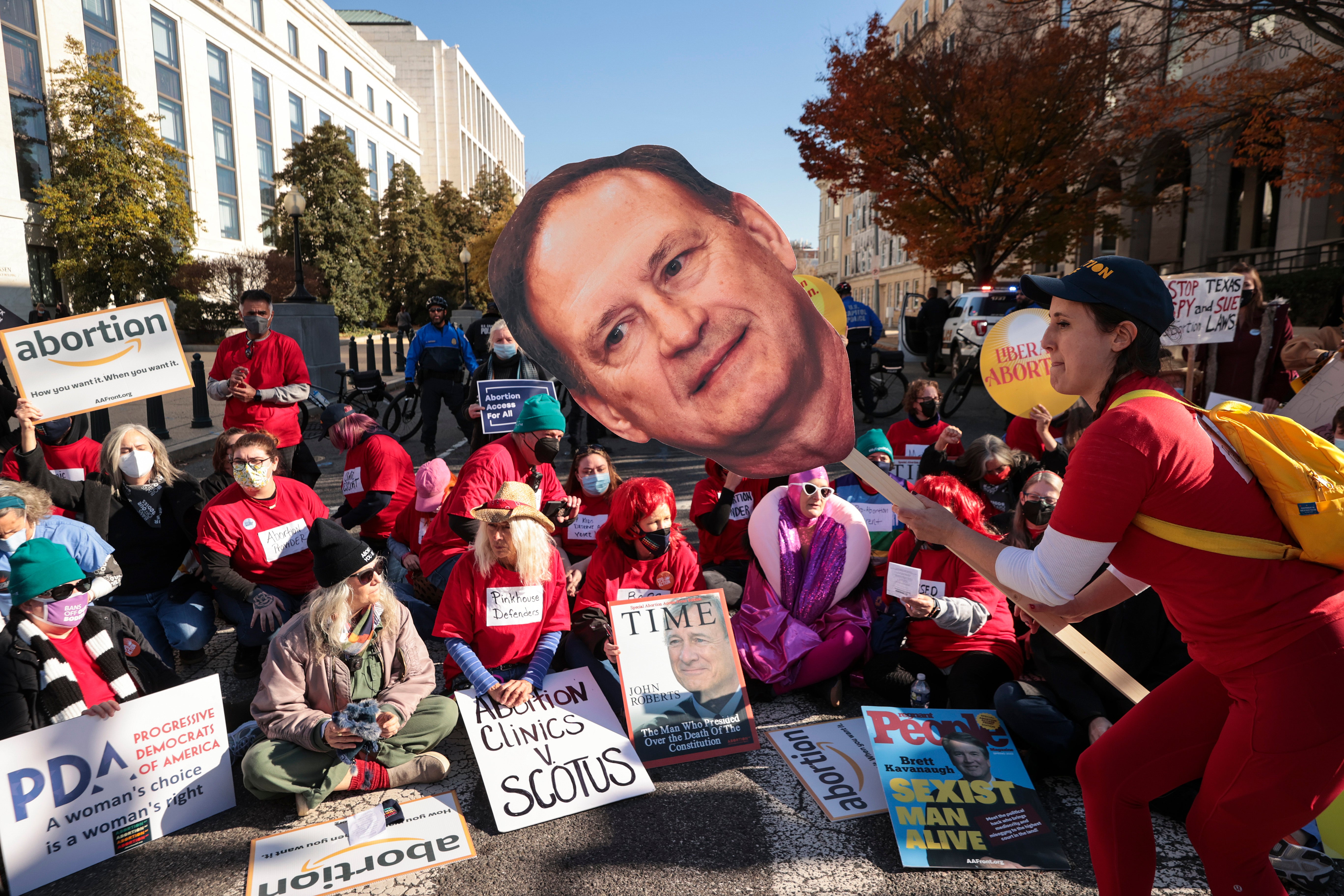 An activist with The Center for Popular Democracy Action holds a photo of US Supreme Court justice Samuel Alito as they block an intersection during a demonstration in front of the US Supreme Court