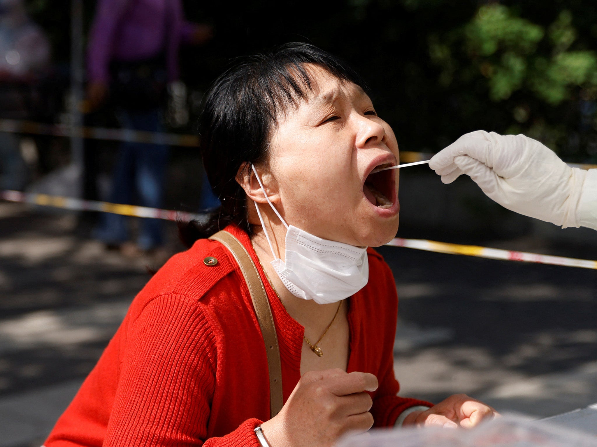 A medical worker collects a swab sample from a Beijing resident
