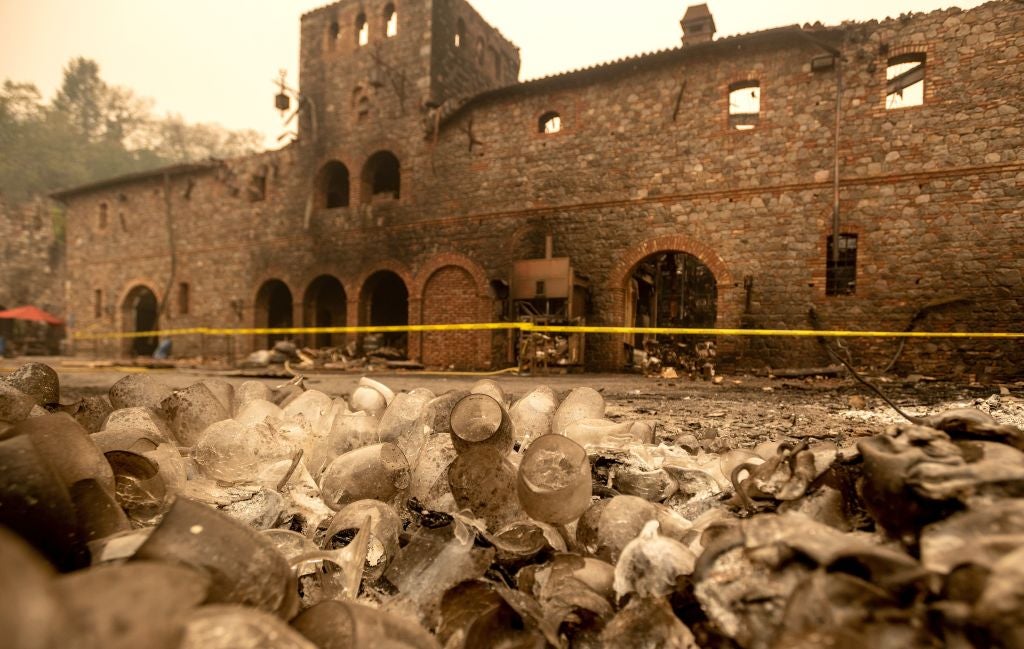 A pile of melted wine glasses sit in front of the burned remains of the Castello Di Amorosa winery following a wildfire in Calistoga, California