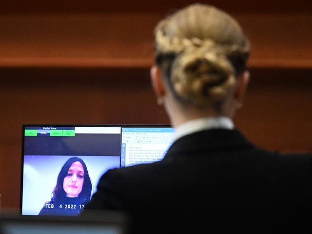 Amber Heard escucha a Erin Falati, exenfermera de Heard, hablar a través de un enlace de video en la sala del tribunal de circuito del condado de Fairfax en Fairfax, Virginia, el 3 de mayo de 2022