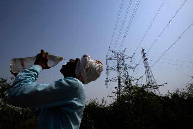 <p>A workers quenches his thirst as a heatwave continues to lash New Delhi</p>