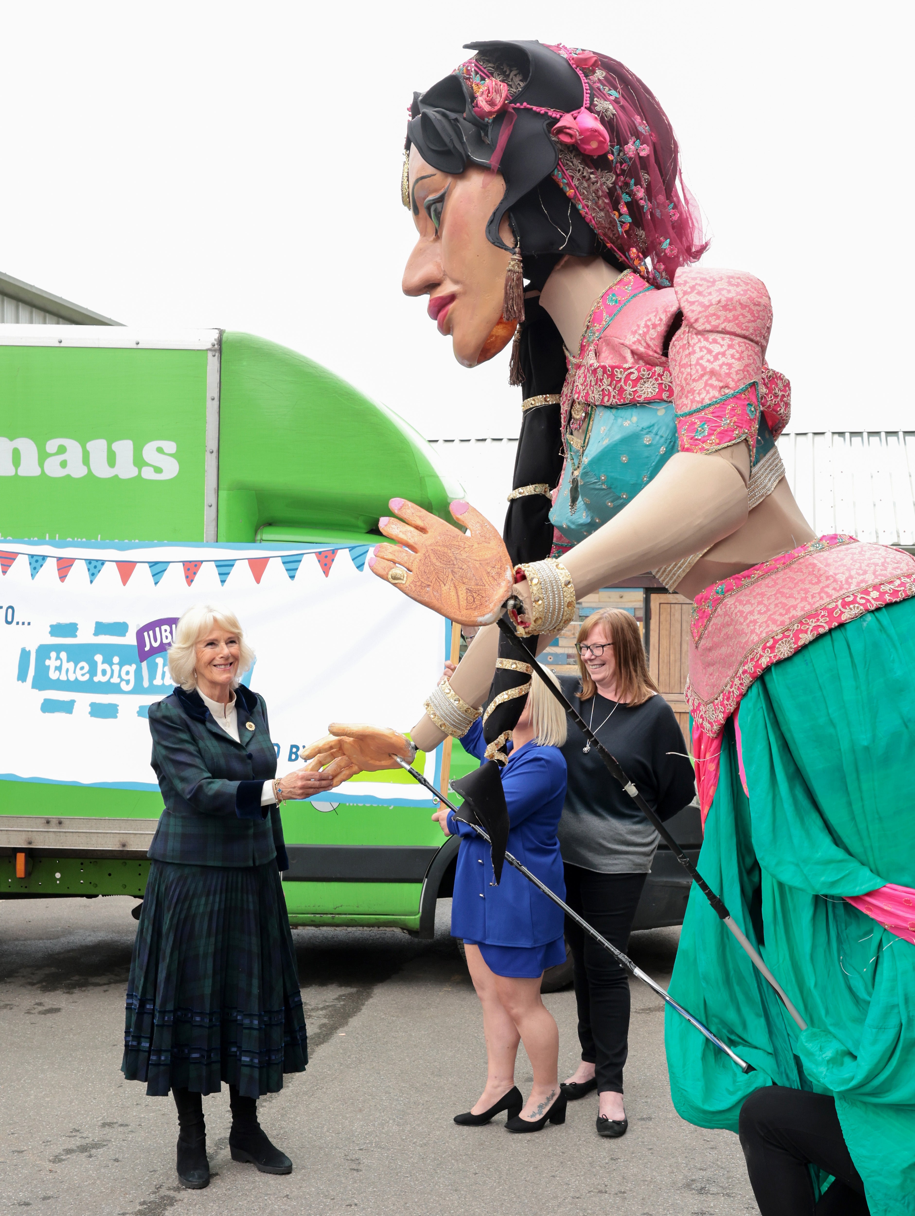 Camilla shakes hands with a giant puppet carnival performer (Chris Jackson/PA)