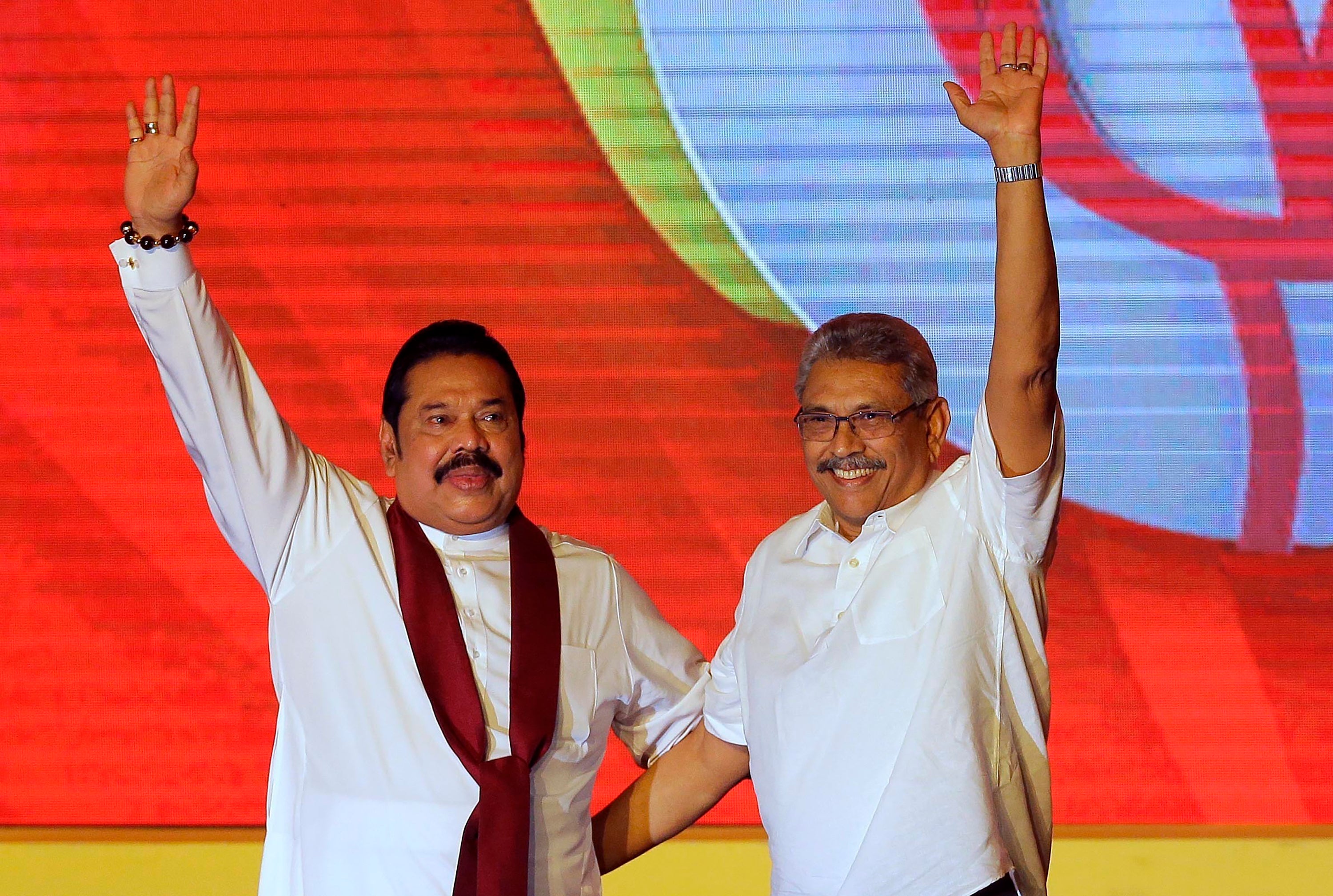 Mahinda Rajapaksa (left) and his brother Gotabaya Rajapaksa wave to supporters during a party convention in 2019