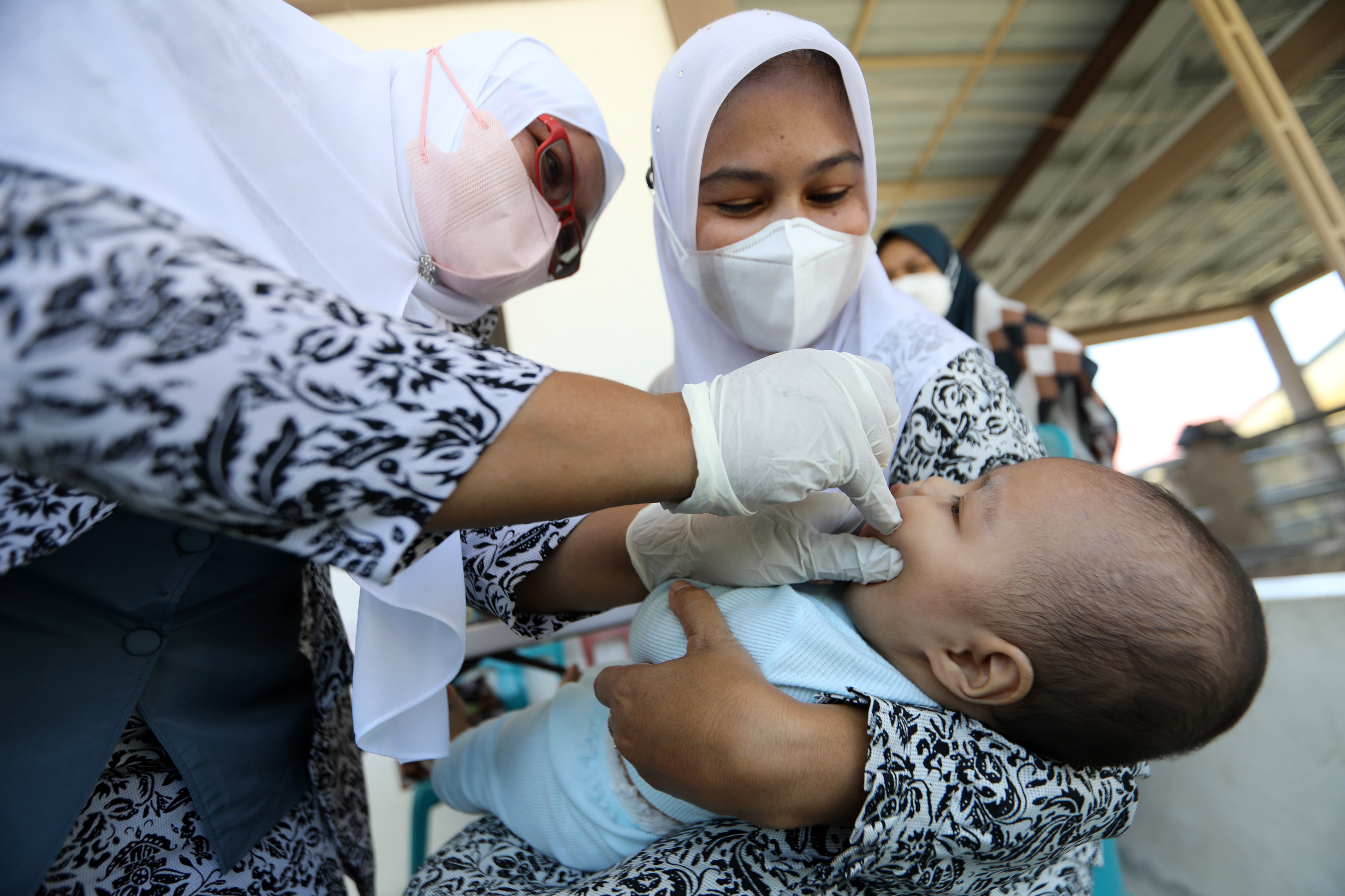 File: A nurse administers a polio vaccine to a child in Indonesia