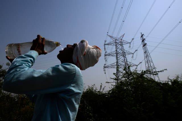 <p>A worker quenches his thirst next to power lines as a heatwave continues to lash Delhi</p>