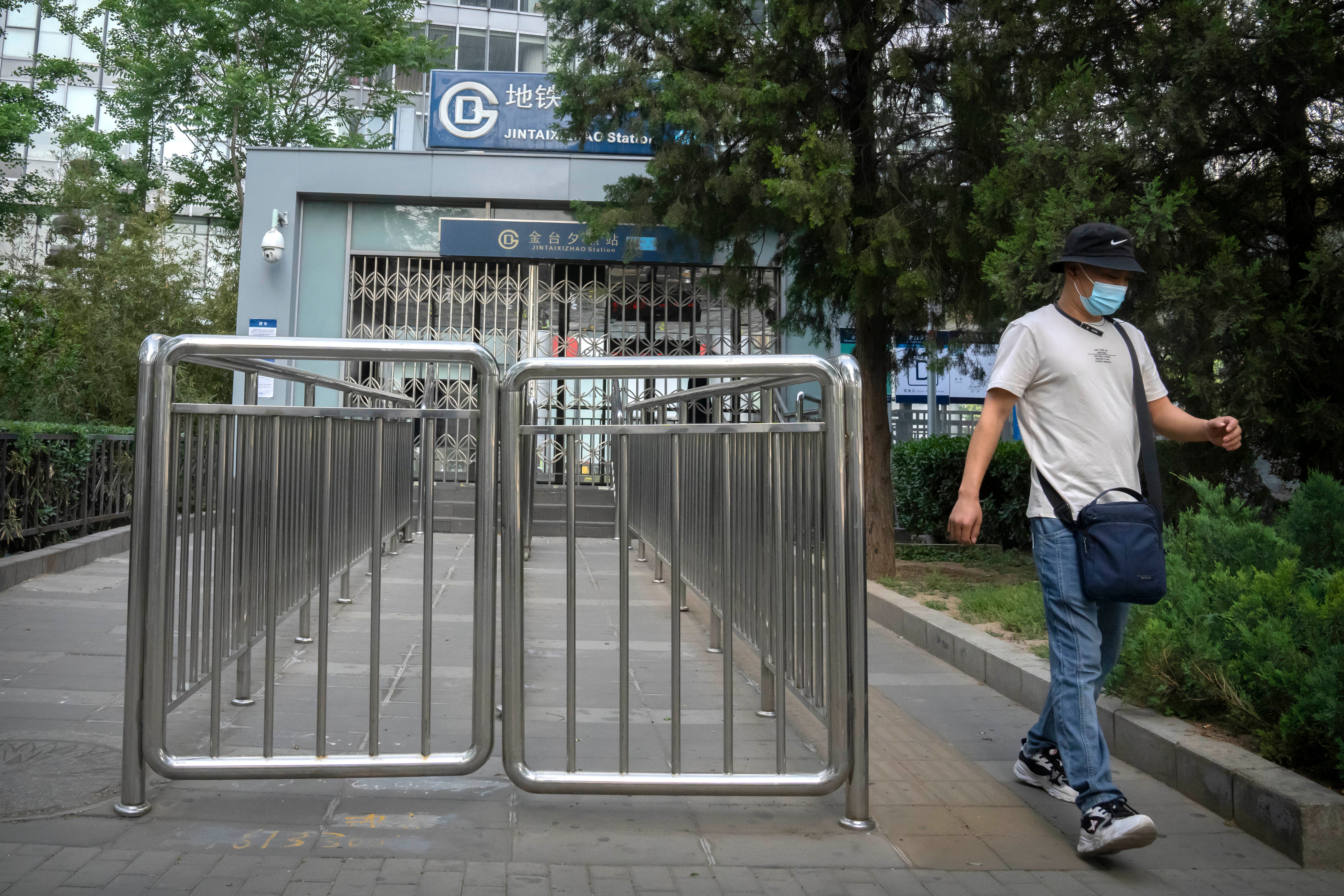 A commuter wearing a face mask walks away after being denied entry to a closed subway station in Beijing, China