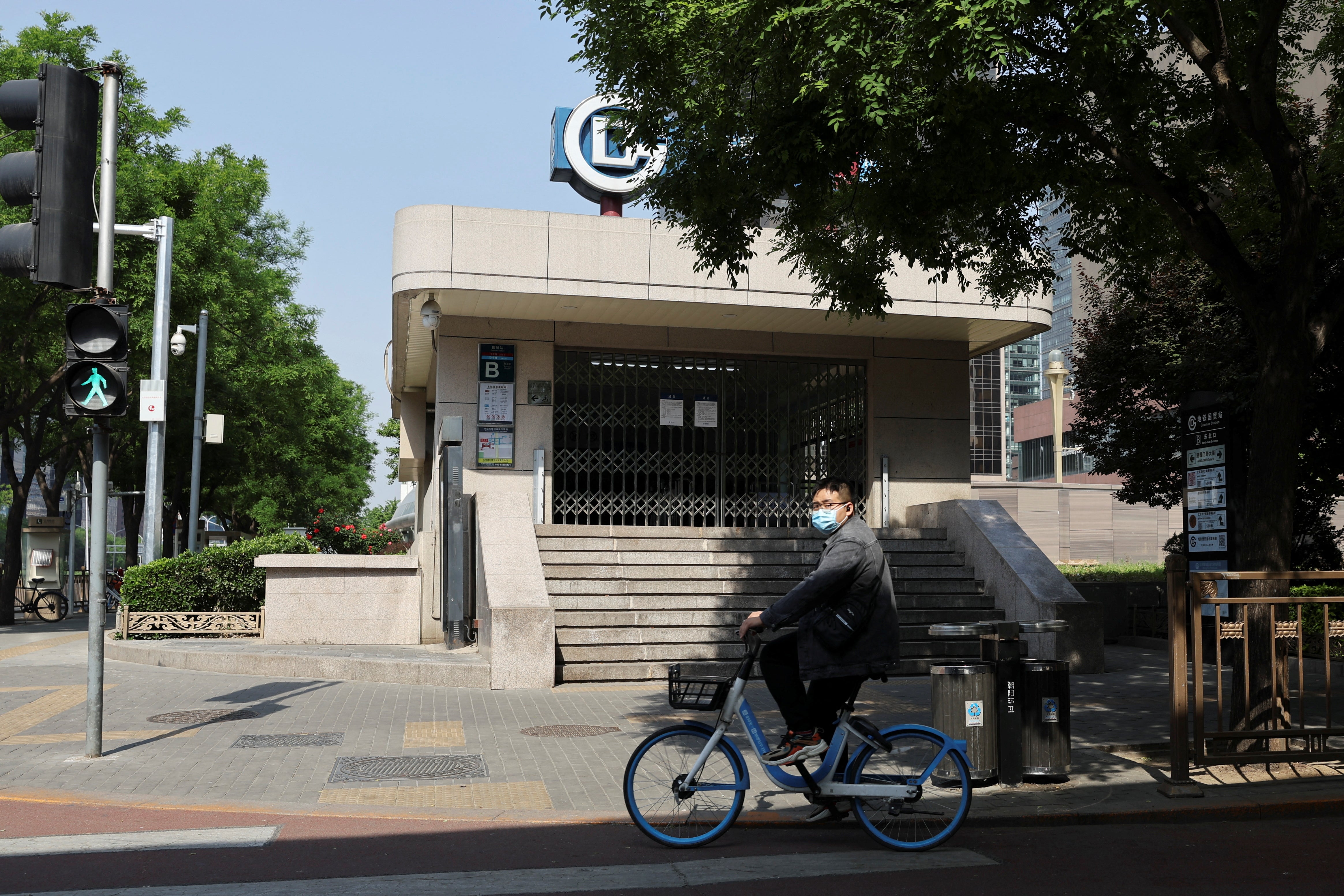 A man rides a shared bicycle past a closed subway station
