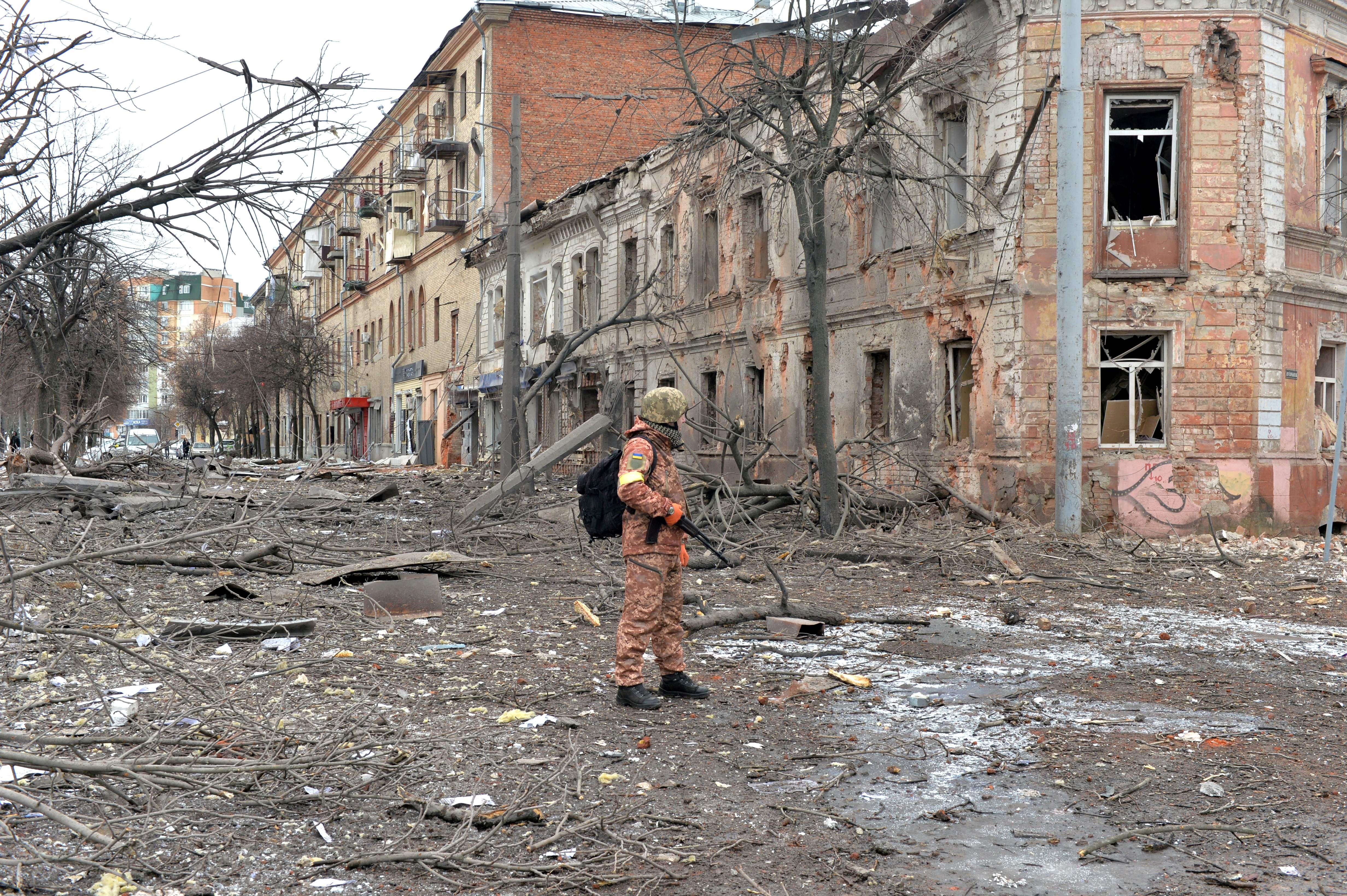 A member of the Ukrainian Territorial Defence Forces looks at the destruction following shelling in Ukraine's second-biggest city of Kharkiv in March