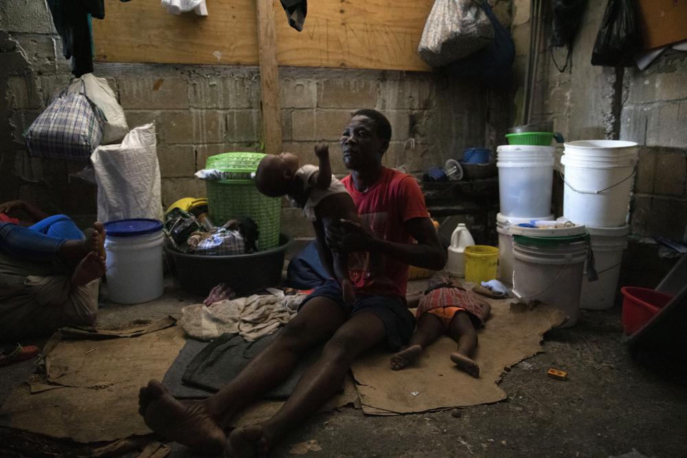A man holds his baby boy at a shelter for families displaced by gang violence in Port-au-Prince, Haiti
