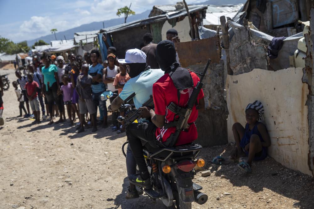 G9 coalition gang members ride a motorcycle through the Wharf Jeremy street market in Port-au-Prince, Haiti