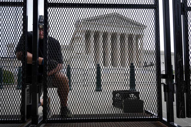 <p>A man secures an un-scalable fence that stands around the US Supreme Court in Washington, DC, on Wednesday </p>