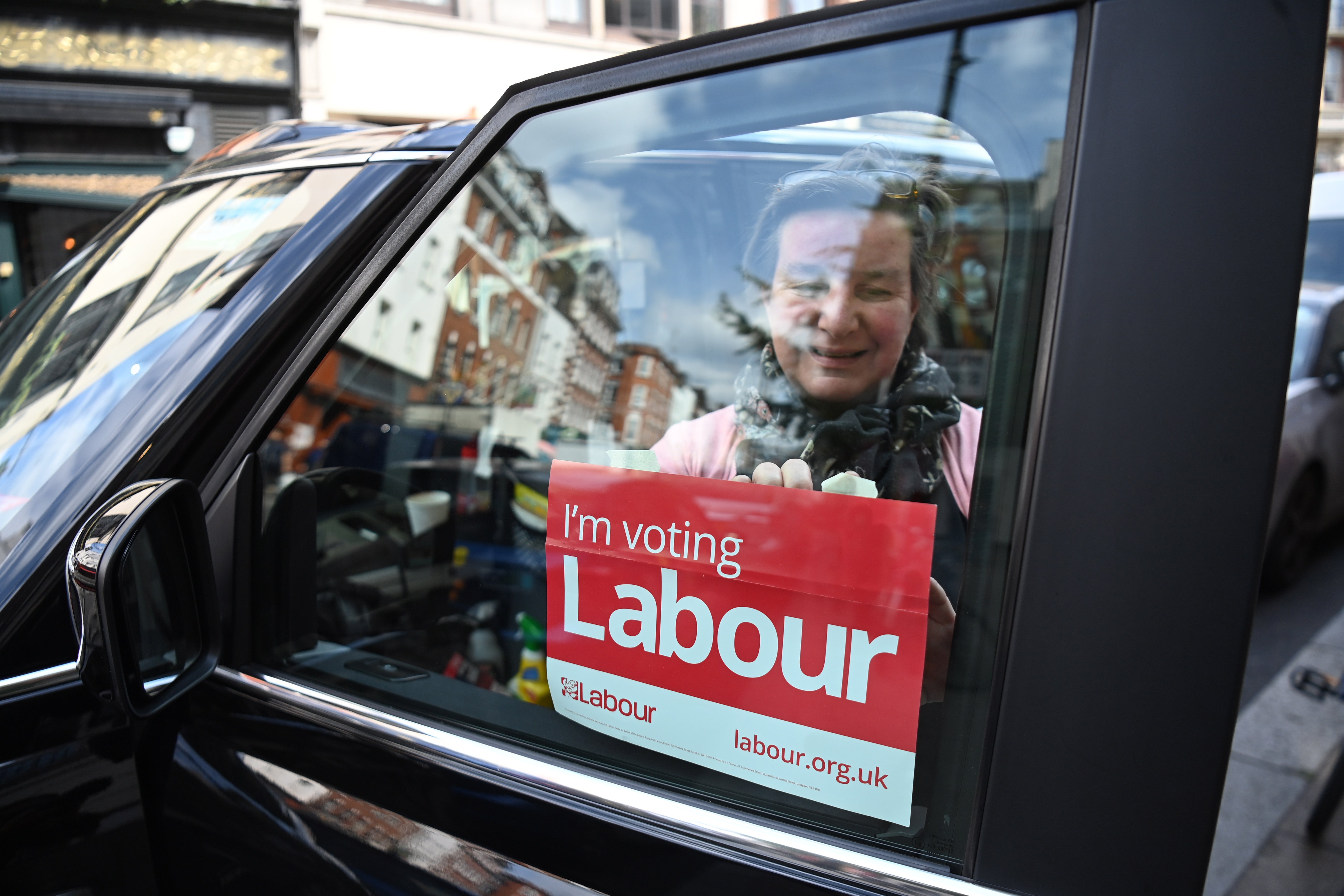 A woman attaches a Labour Party sign to her taxi in London on 5 May