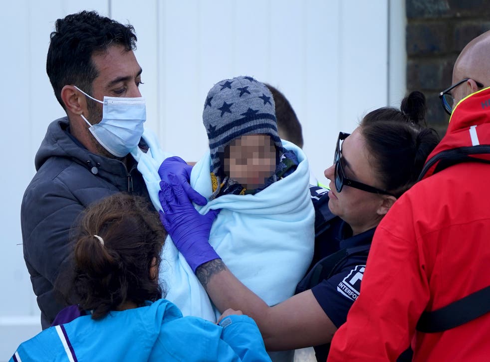 <p>A young child wrapped in a blanket is among a group of people thought to be migrants brought in to Dover, Kent </p>