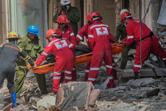 <p>Rescuers recover a body at the site of Friday's deadly explosion that destroyed the five-star Hotel Saratoga, in Havana, Cuba, on 7 May 2022 </p>