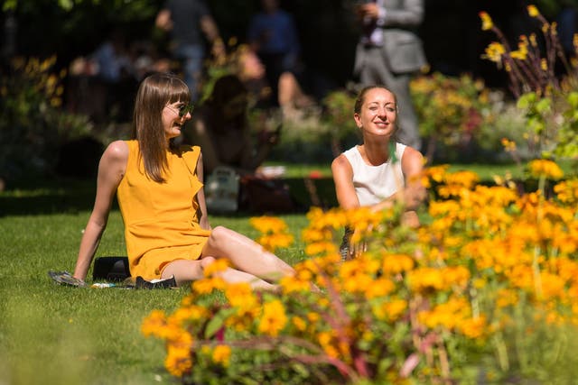 Two women sit in the sun in Whitehall Gardens, Westminster (Dominic Lipinski/PA)