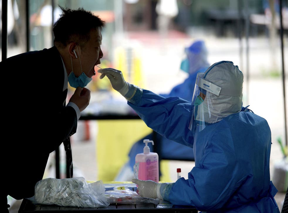 <p>A health worker takes a sample from a man to test for the Covid-19 infection in Beijing</p>