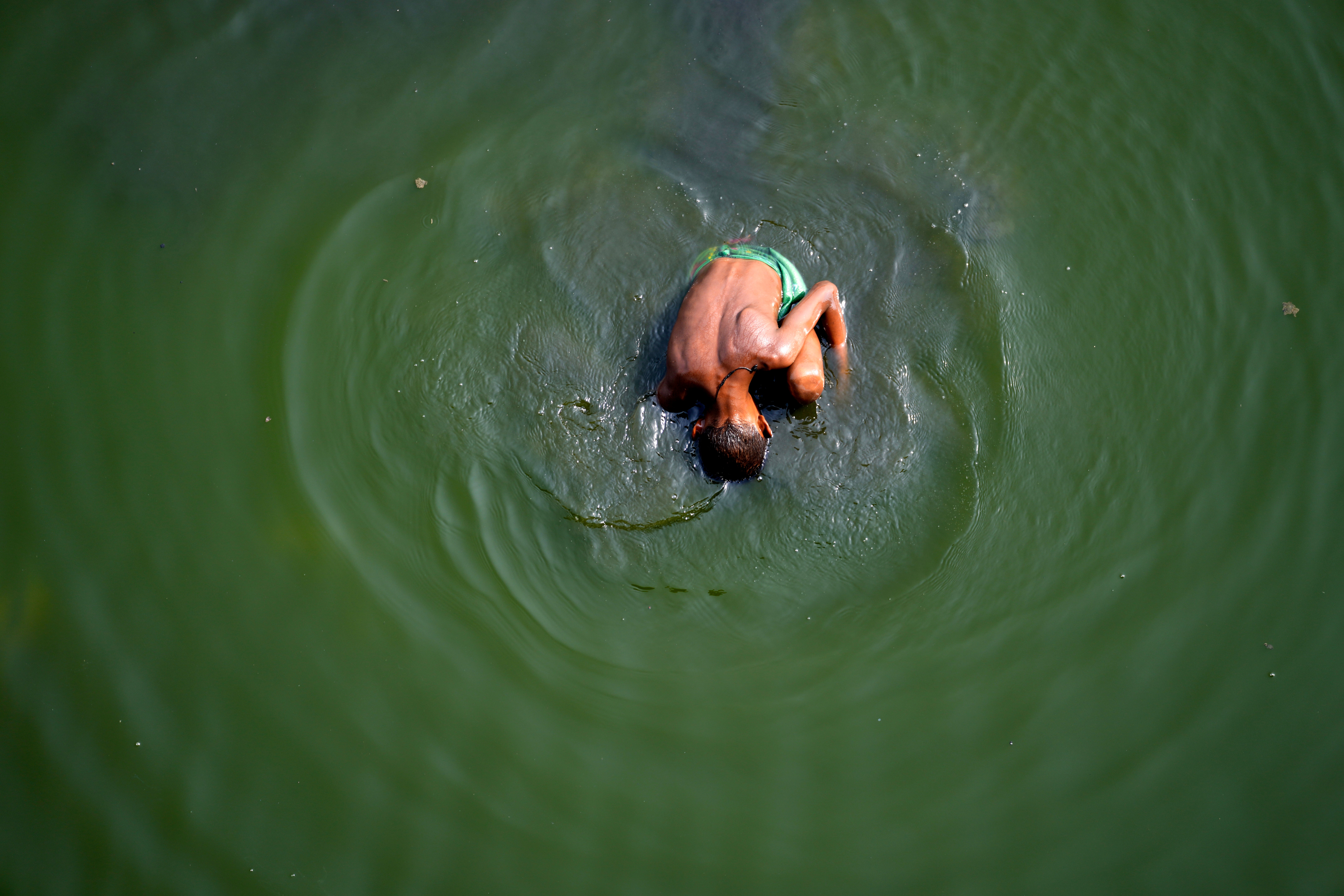 A boy searches for coins in river Yamuna where water levels have drastically reduced following a heatwave in India