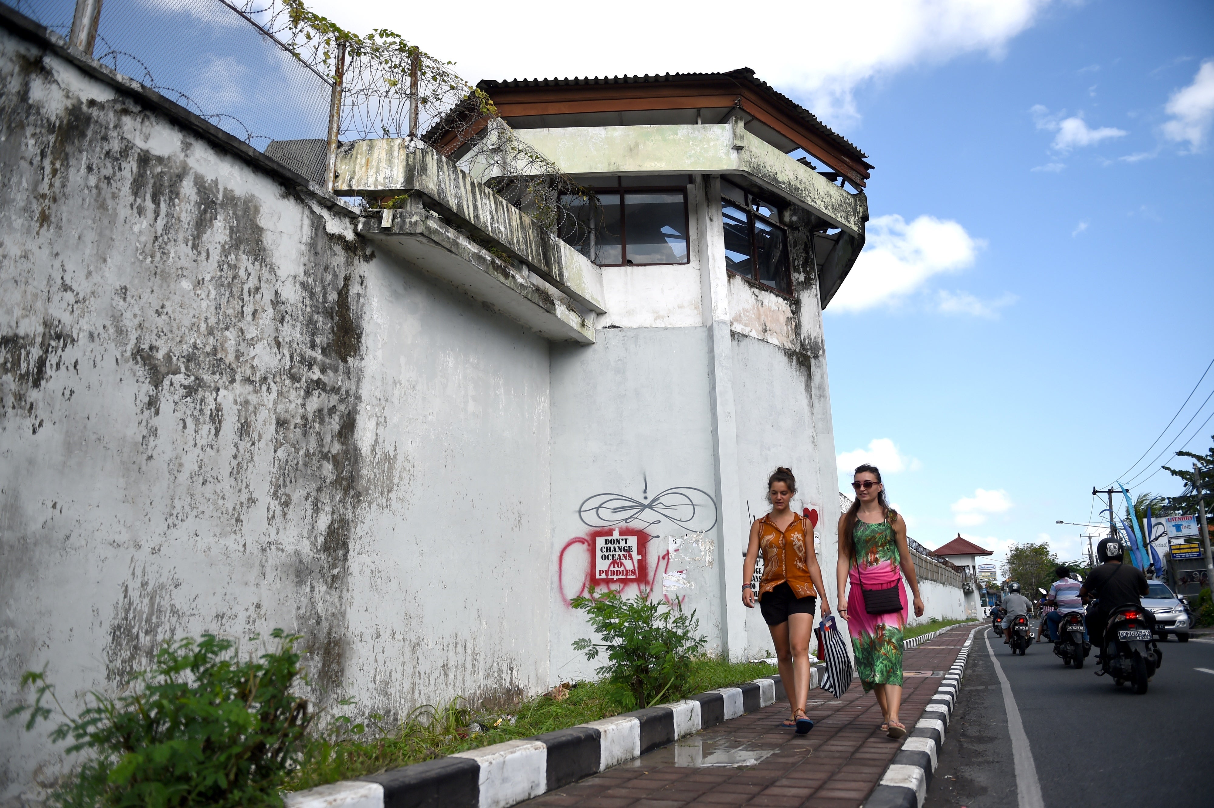 Tourists walk by the perimeter wall of Kerobokan in 2017