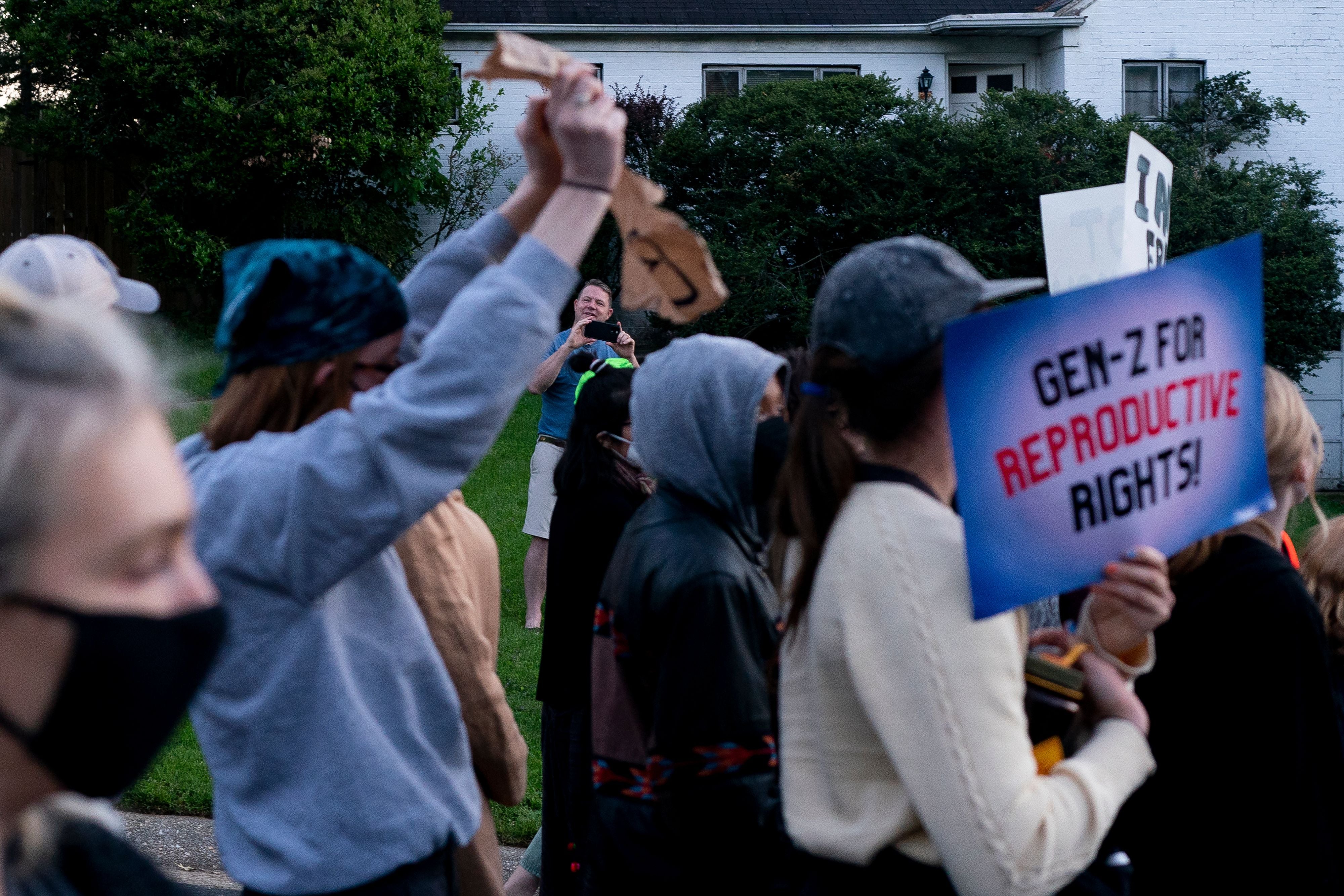 An on-looker records on their phone as pro-choice demonstrators march to the house of US Supreme Court Justice Samuel Alito in Alexandria, Virginia, on May 9, 2022