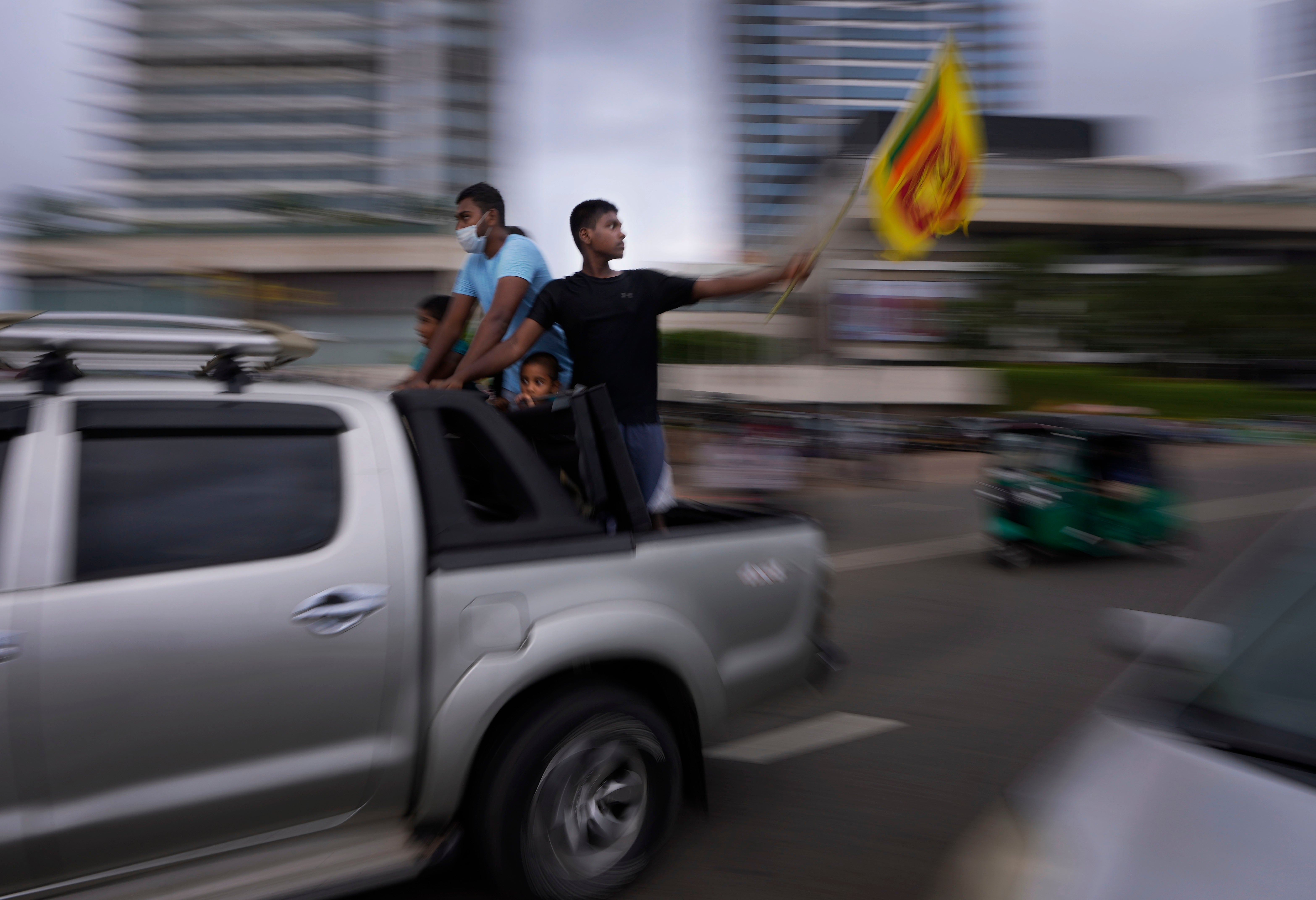 Sri Lankans wave a national flag during Tuesday’s curfew in Colombo
