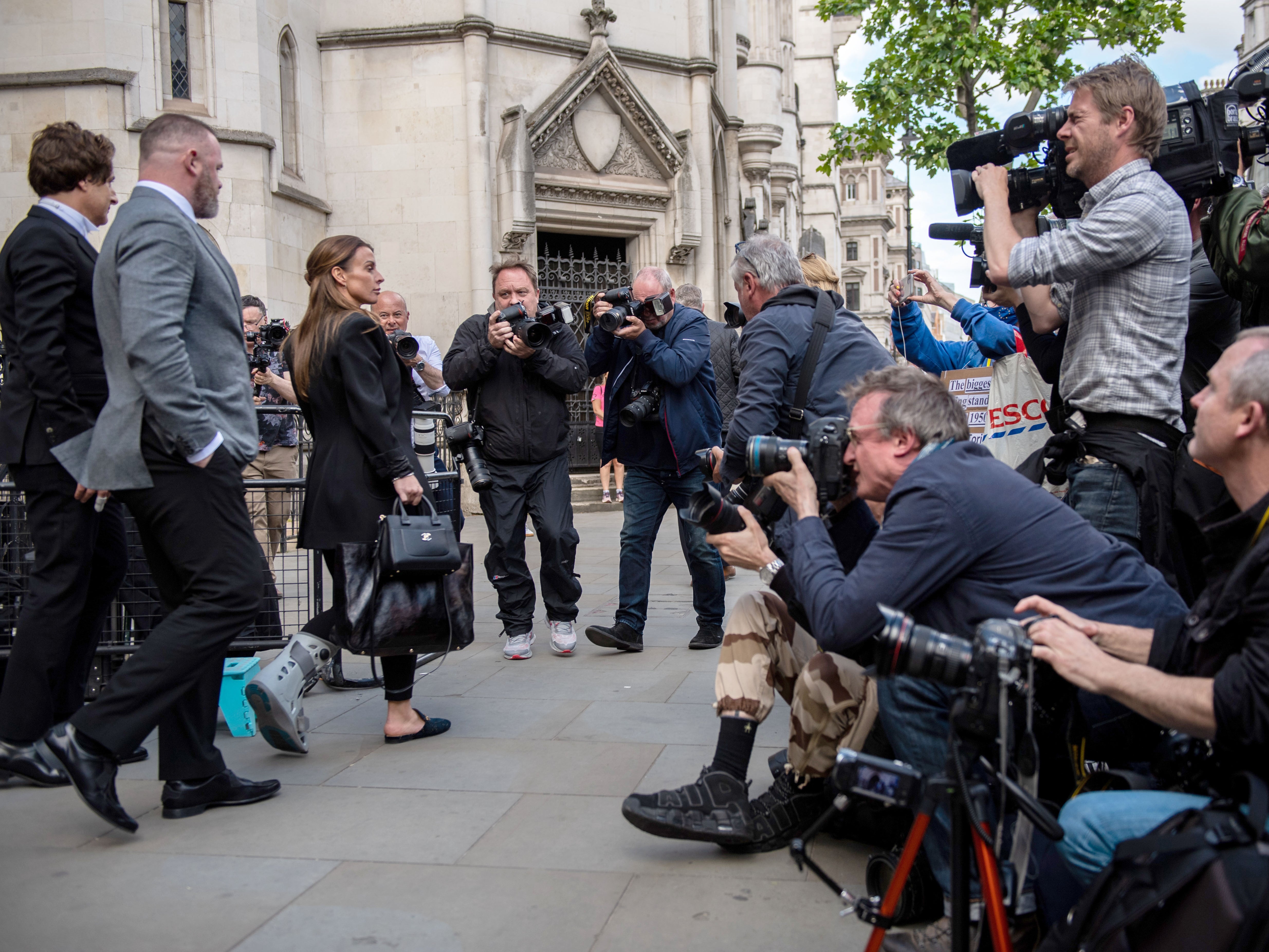 Members of the press photograph and film Coleen Rooney and her husband Wayne Rooney leaving the Royal Courts of Justice on Tuesday