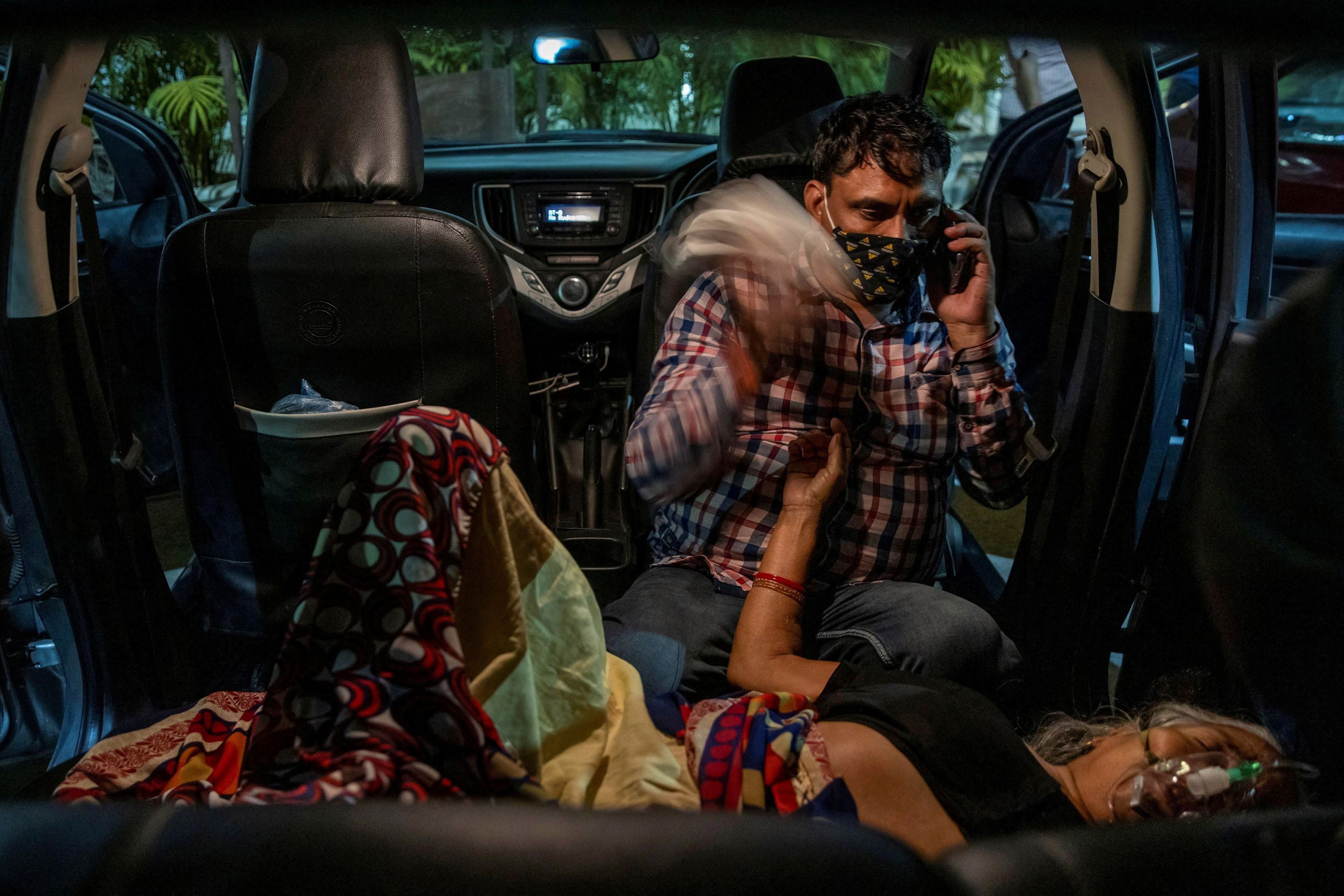 Manoj Kumar waves a handkerchief from the back seat of his vehicle at his mother Vidhya Devi as she receives oxygen in the parking lot of a Gurudwara in Ghaziabad on 24 April 2021