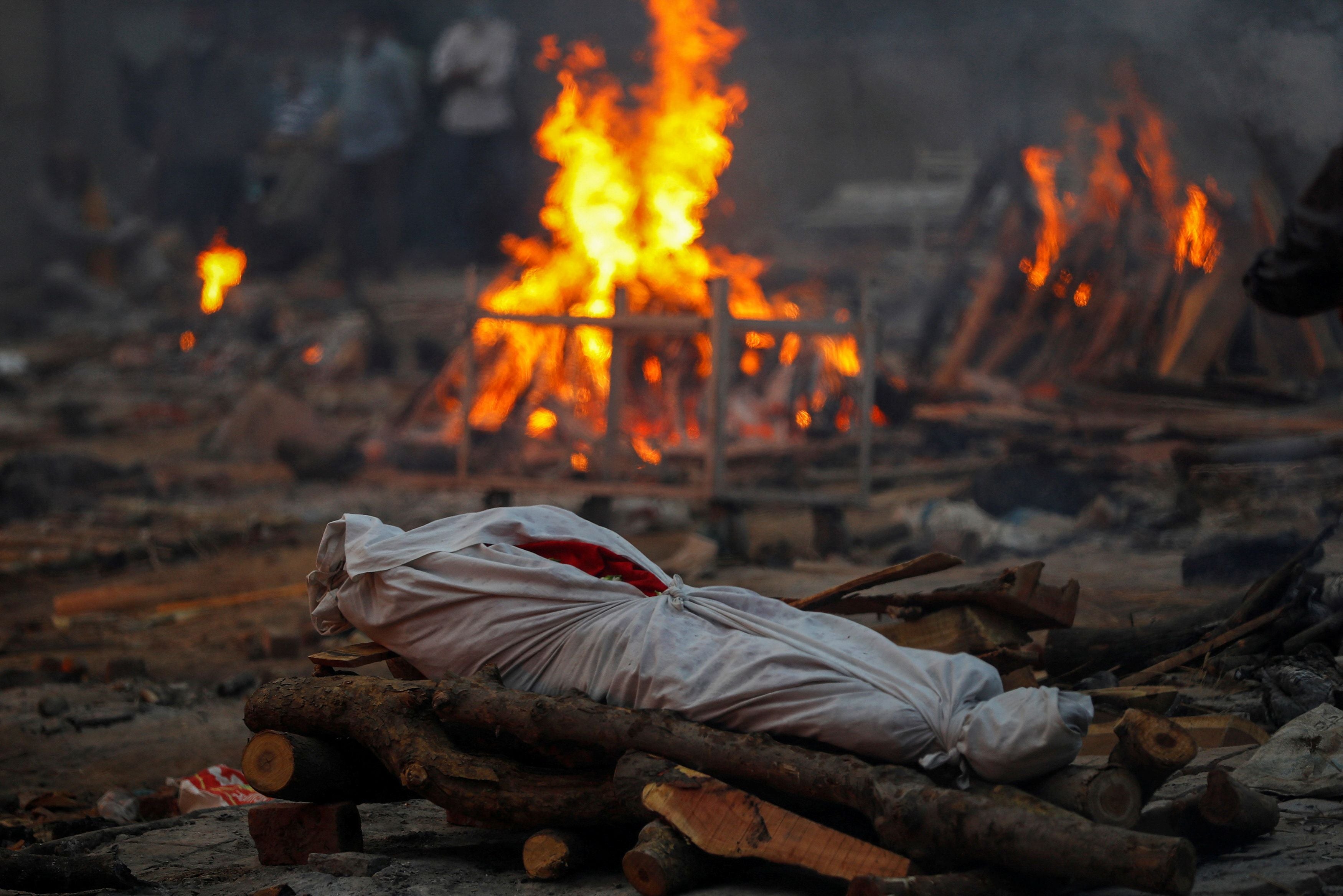 The body of a person who died from coronavirus lies on a funeral pyre during a mass cremation in New Delhi on 1 May 2021