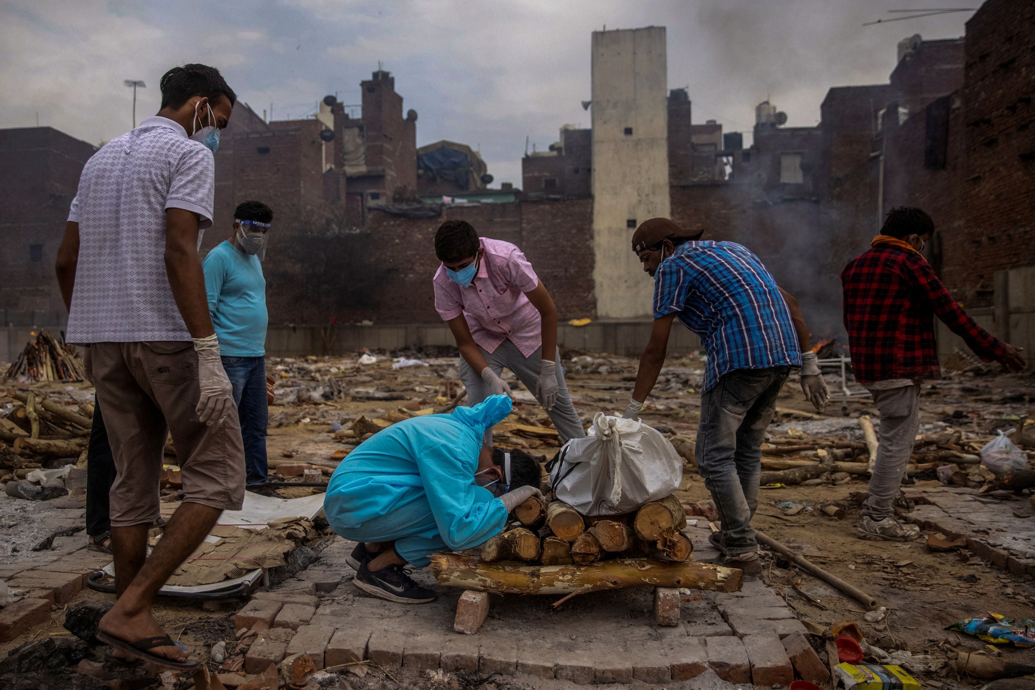 Pranav Mishra, 19, kneels toward the body of his mother Mamta Mishra who died aged 45 from coronavirus, ahead of her cremation in New Delhi on 4 May 2021