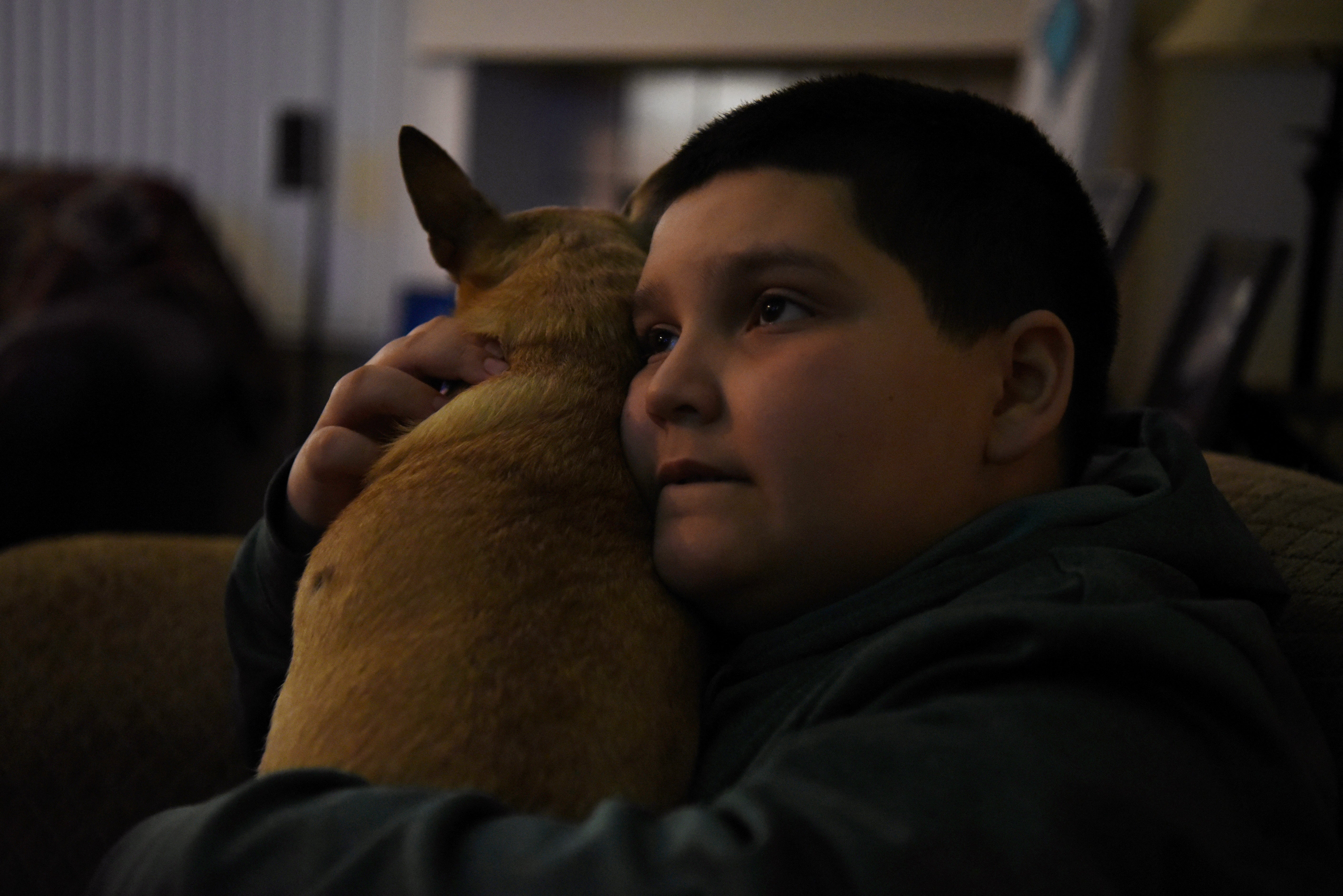 Aidan Garza hugs the family dog while watching television at home