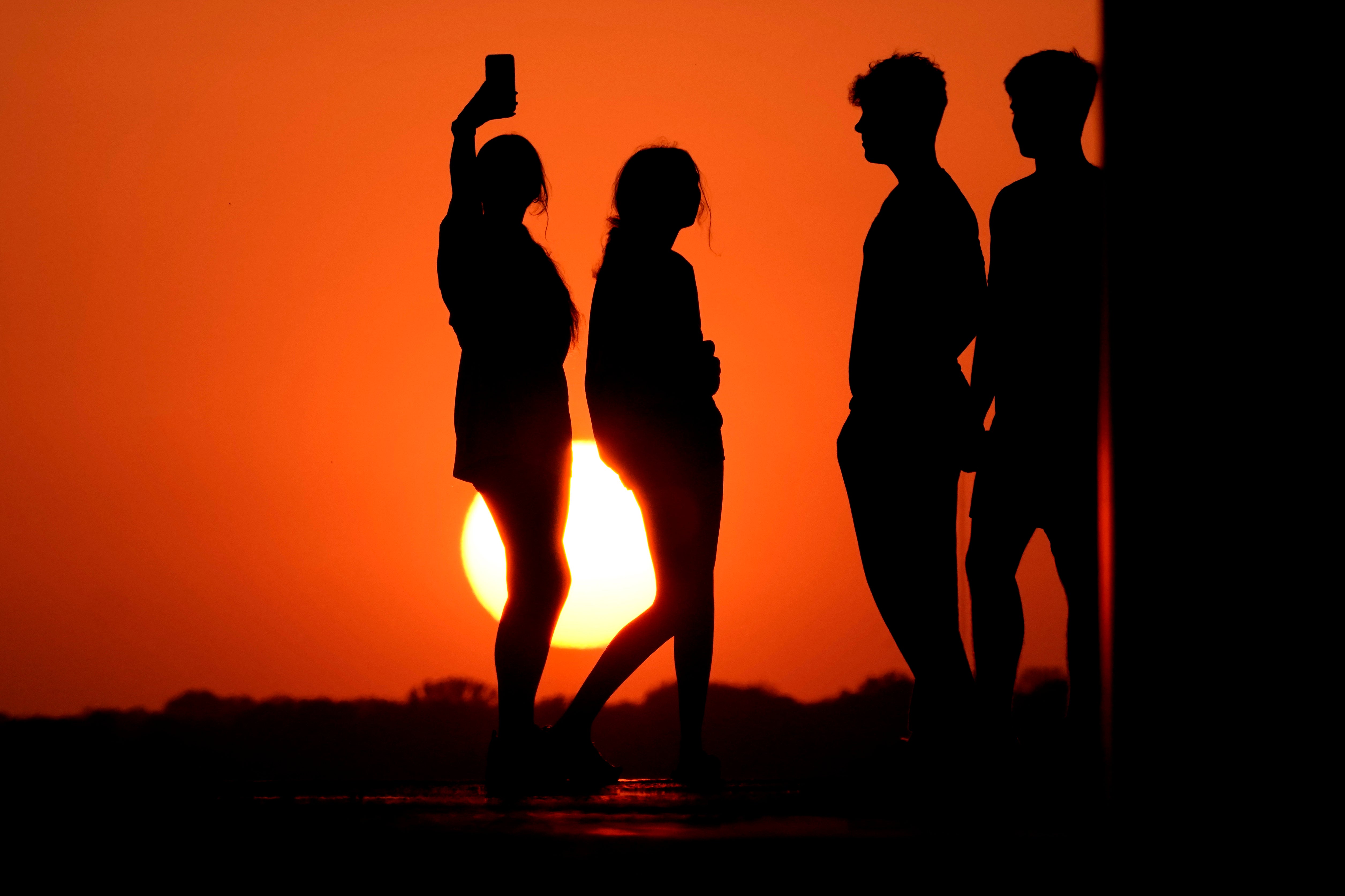 People in Kansas City, MO on Wednesday against a sunset turned vibrant orange by smoke from the New Mexico fires drifting east