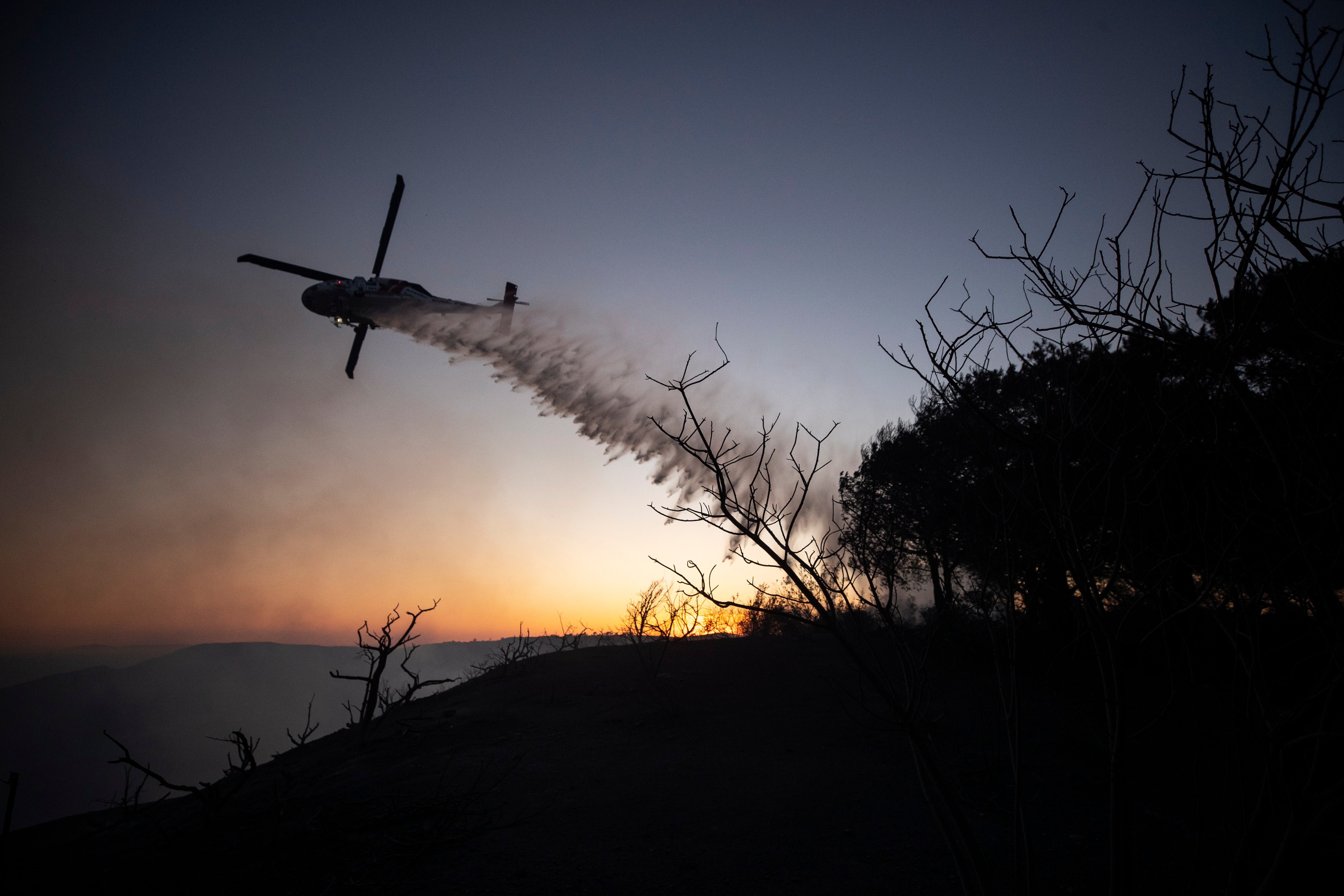 A helicoper douses the brush around the Coastal Fire in Laguna Niguel, CA