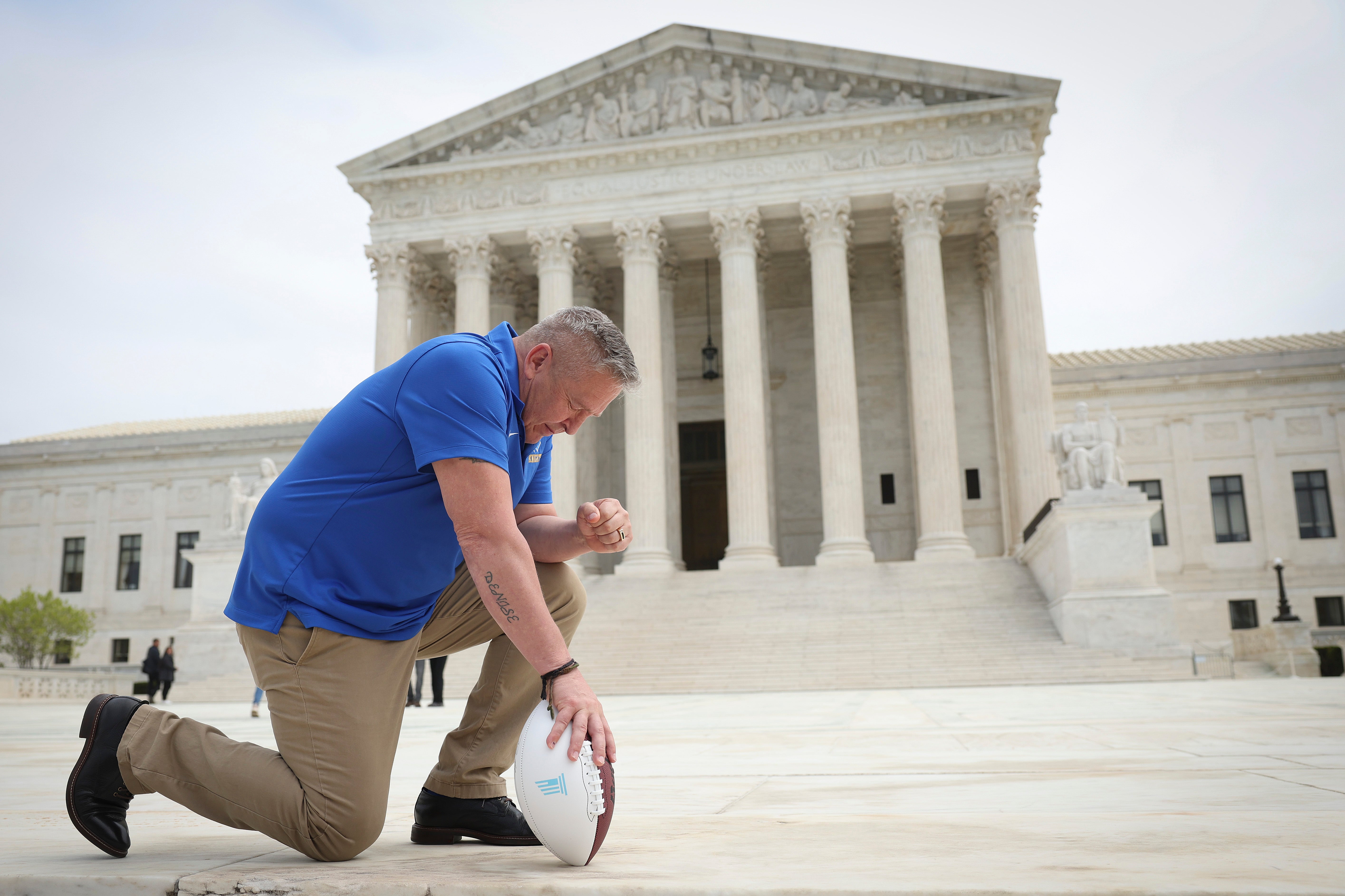 Former Bremerton High School football coach Joe Kennedy takes a knee in front of US Supreme Court