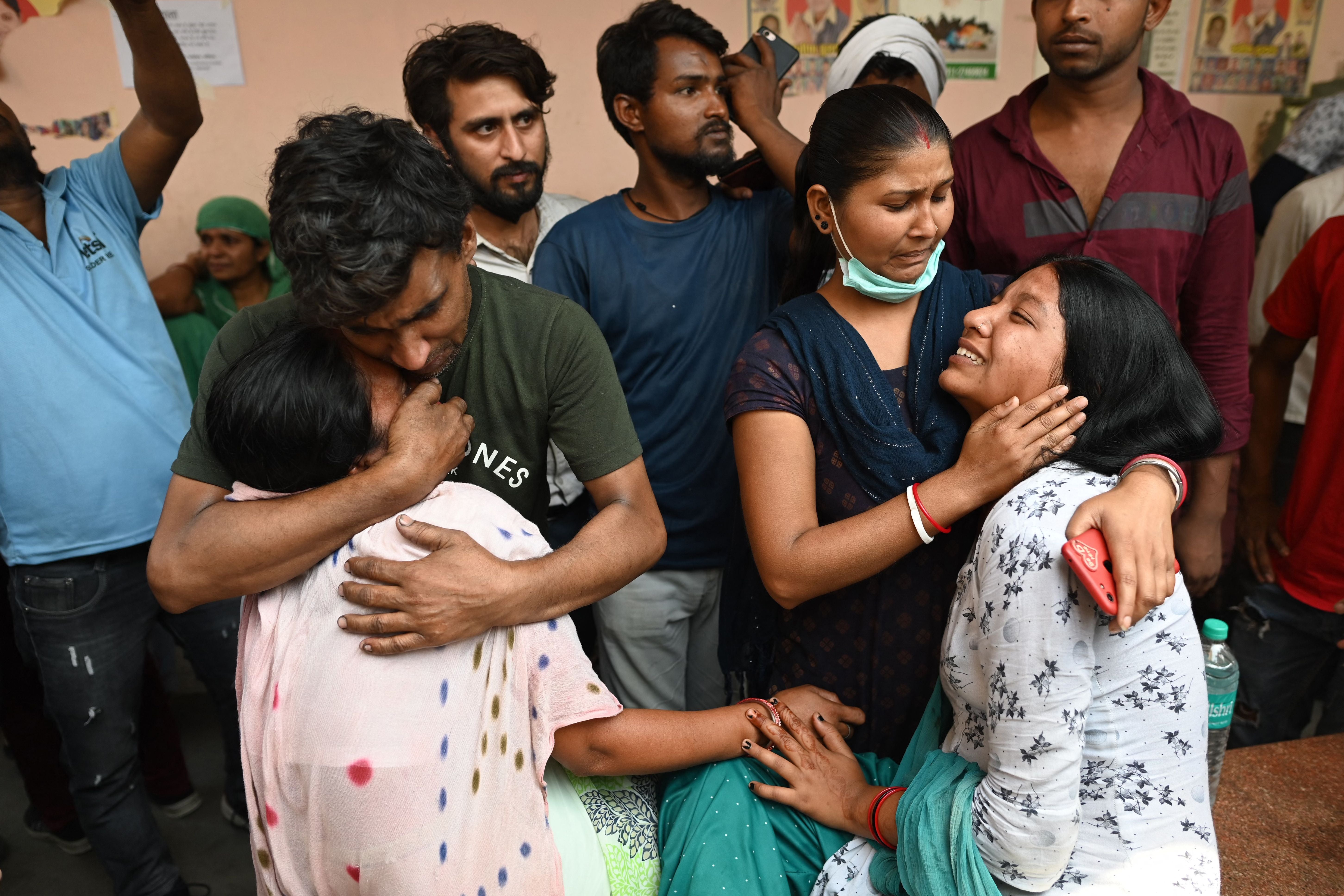 Relatives grief at a hospital as they wait for the body of their loved one a day after a fire broke out at a commercial building in Delhi