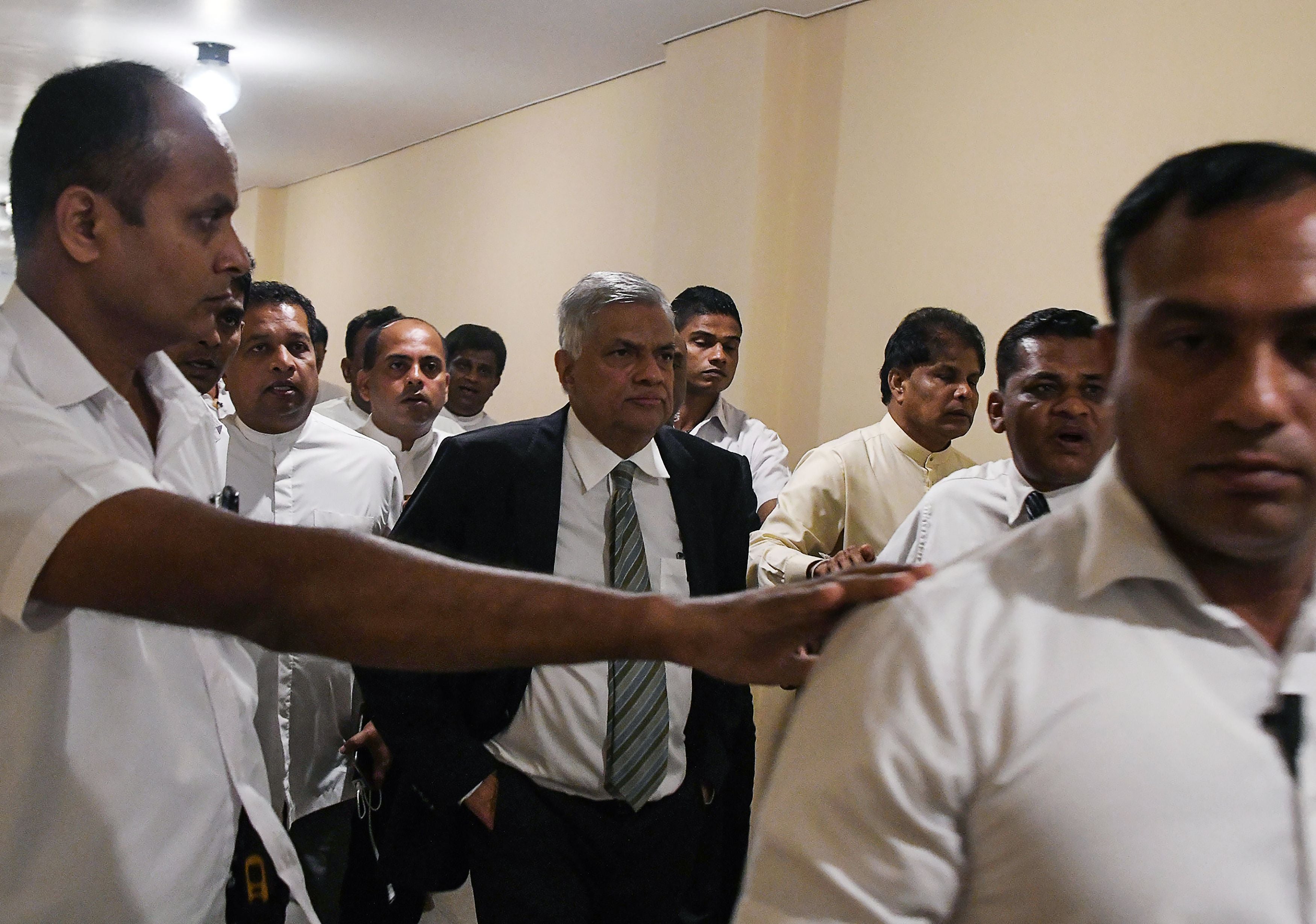 Sri Lankan prime minister Ranil Wickremesinghe (Centre) leaves parliament escorted by security personnel and aides in Colombo