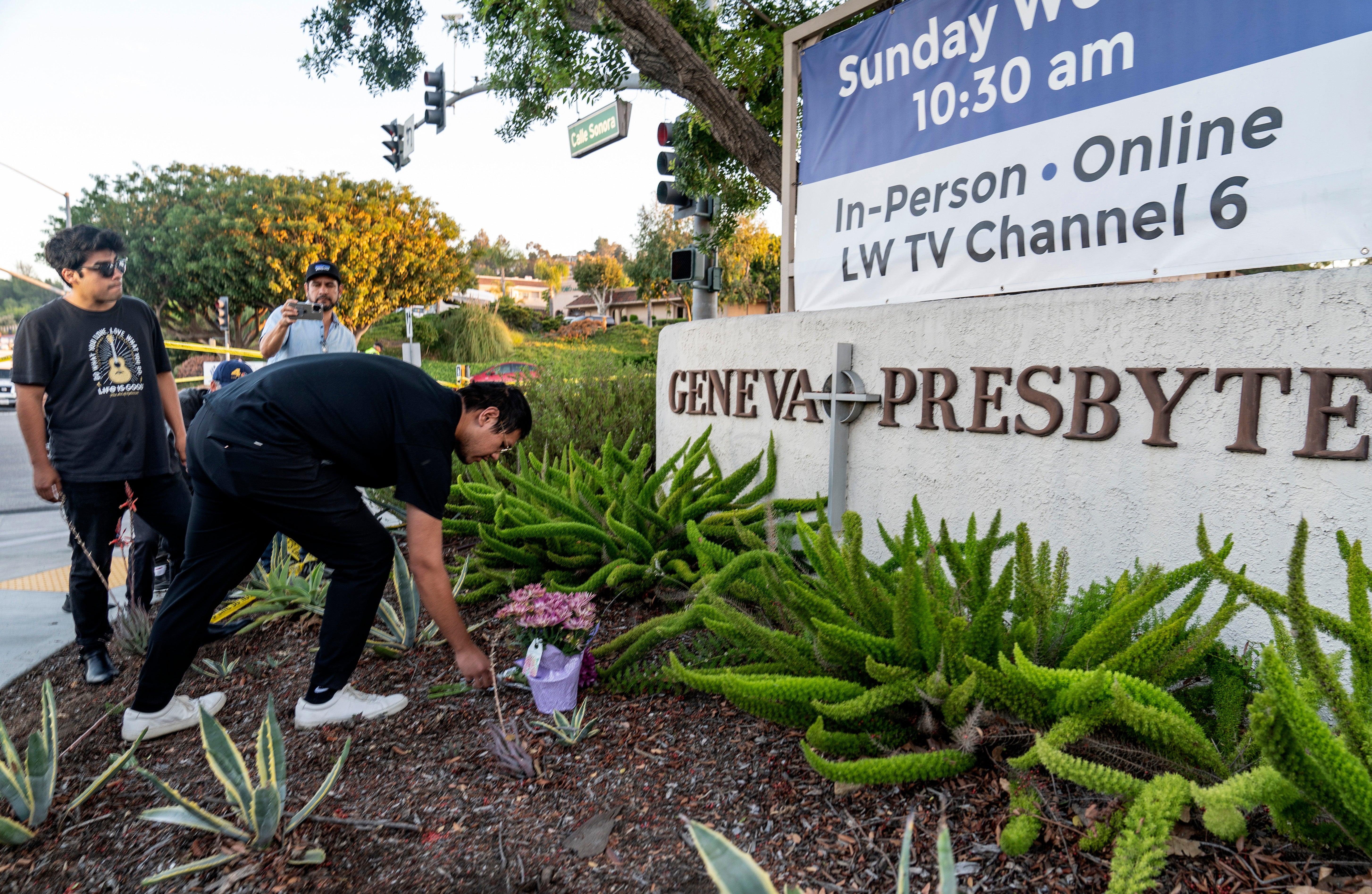Hector Gomez, left, and Jordi Poblete, worship leaders at the Mariners Church Irvine, leave flowers outside the Geneva Presbyterian Church in Laguna Woods