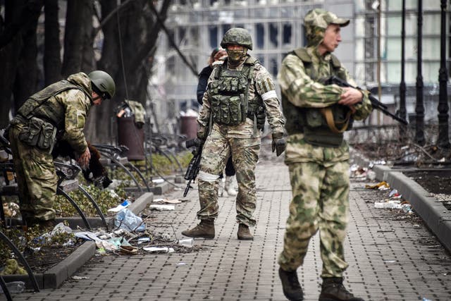 <p>Russian soldiers walk along a street in Mariupol on 12 April</p>