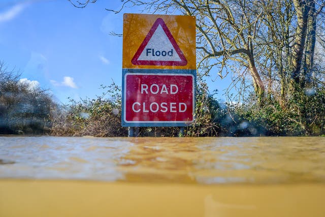A road closed sign pokes out above floodwater (Ben Birchall/PA)