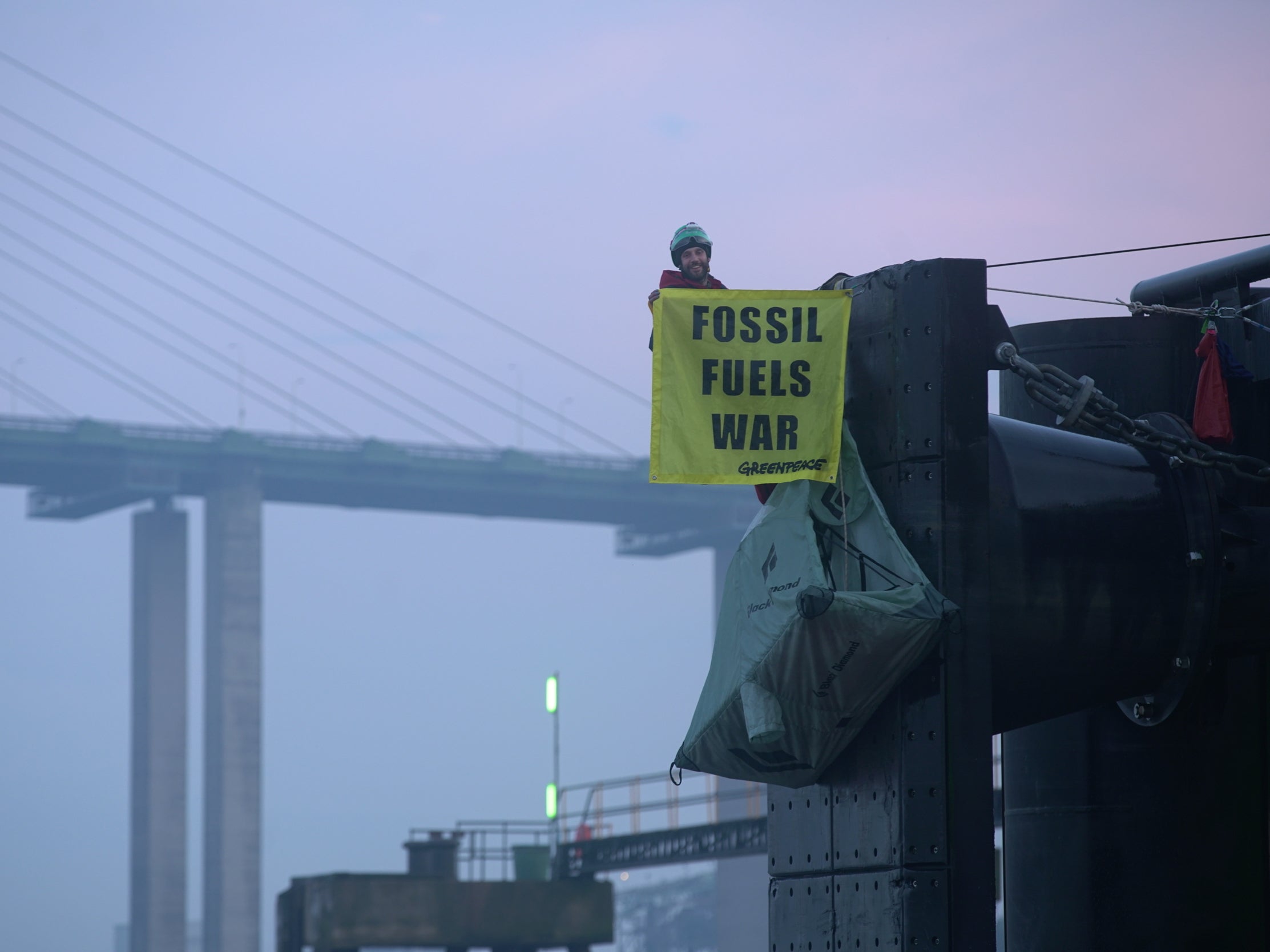 Greenpeace climbers hang off a berth at a UK port