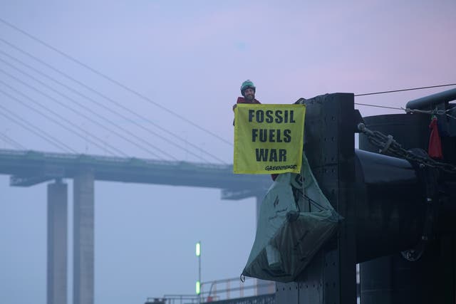 <p>Greenpeace climbers hang off a berth at a UK port</p>