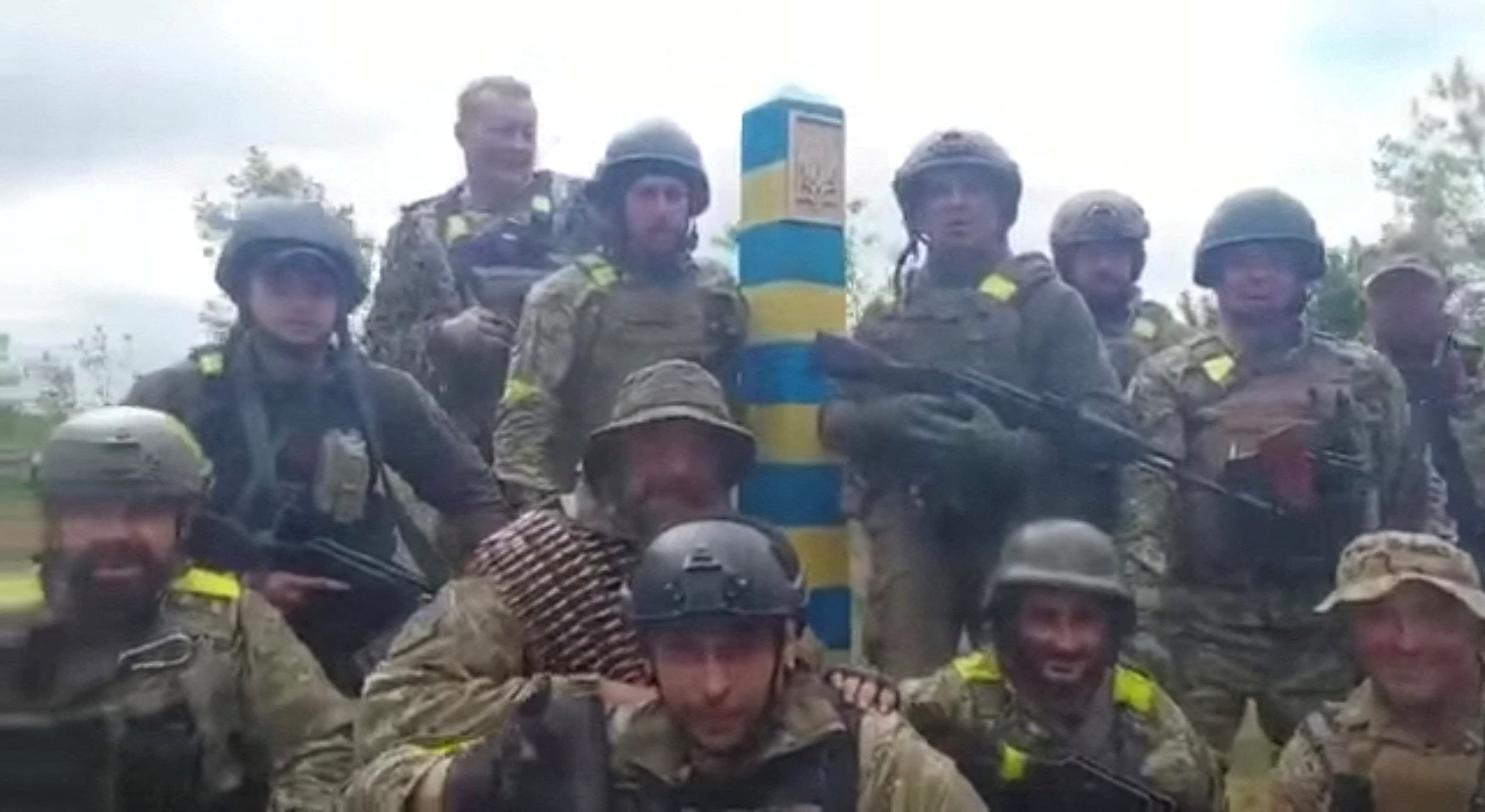 A dozen Ukrainian troops stand beside what is said to be a border post near Kharkiv, Ukraine