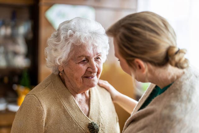 <p>A health visitor talking to a senior citizen during a home visit</p>