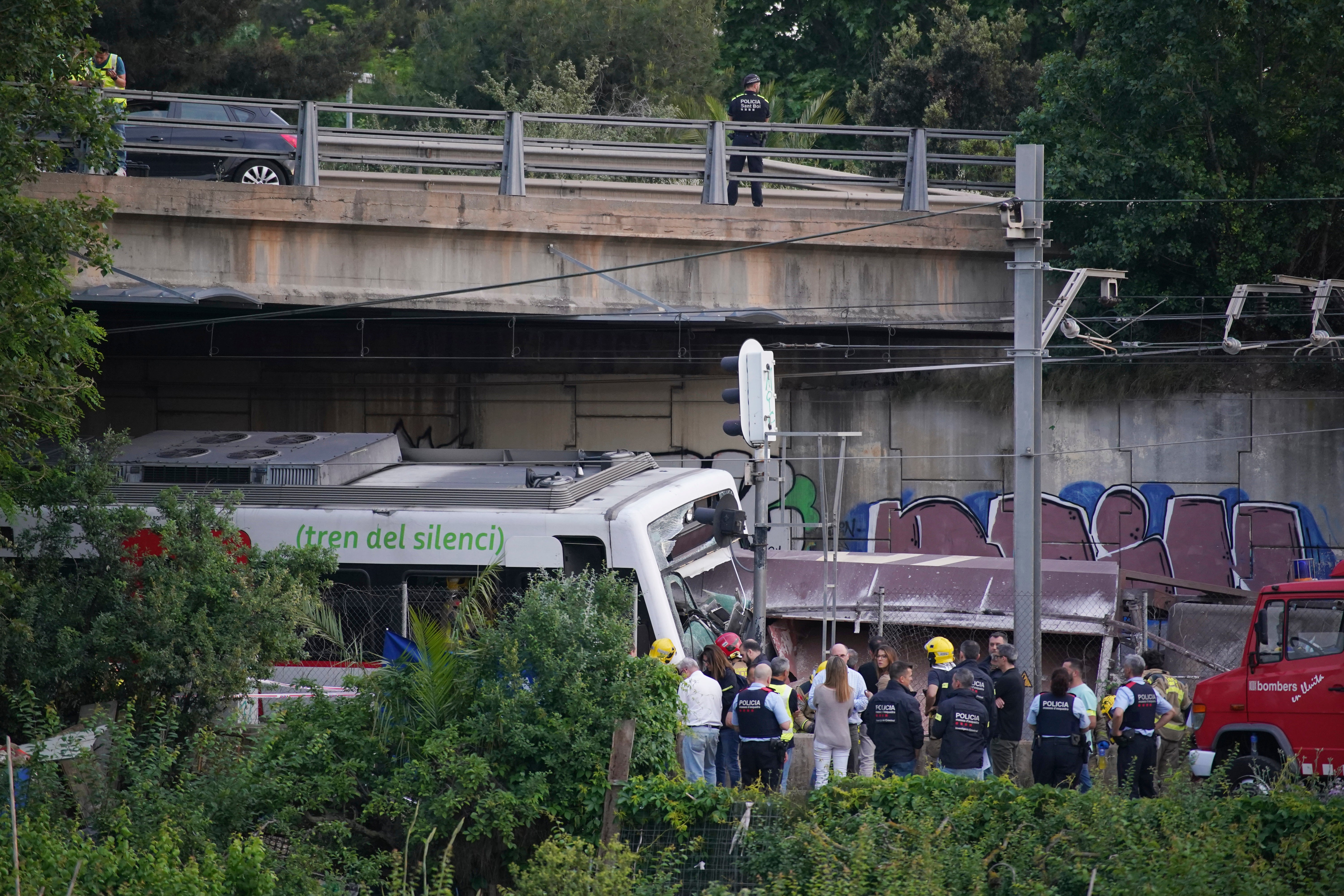 Police and rescue workers stand by the wreckage after a train crash in Sant Boi near Barcelona