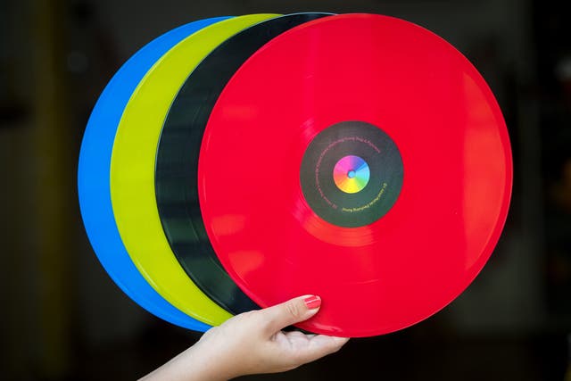 <p>A woman holds 12 inch vinyl records (Dominic Lipinski/PA)</p>