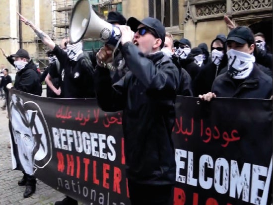 Alex Davies speaking at a 2016 National Action demonstration in York, in front of a banner containing the words ‘Refugees not welcome: Hitler was right.’