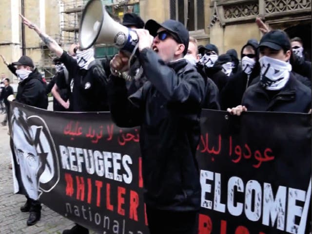 <p>Alex Davies speaking at a 2016 National Action demonstration in York, in front of a banner containing the words ‘Refugees not welcome: Hitler was right’  </p>