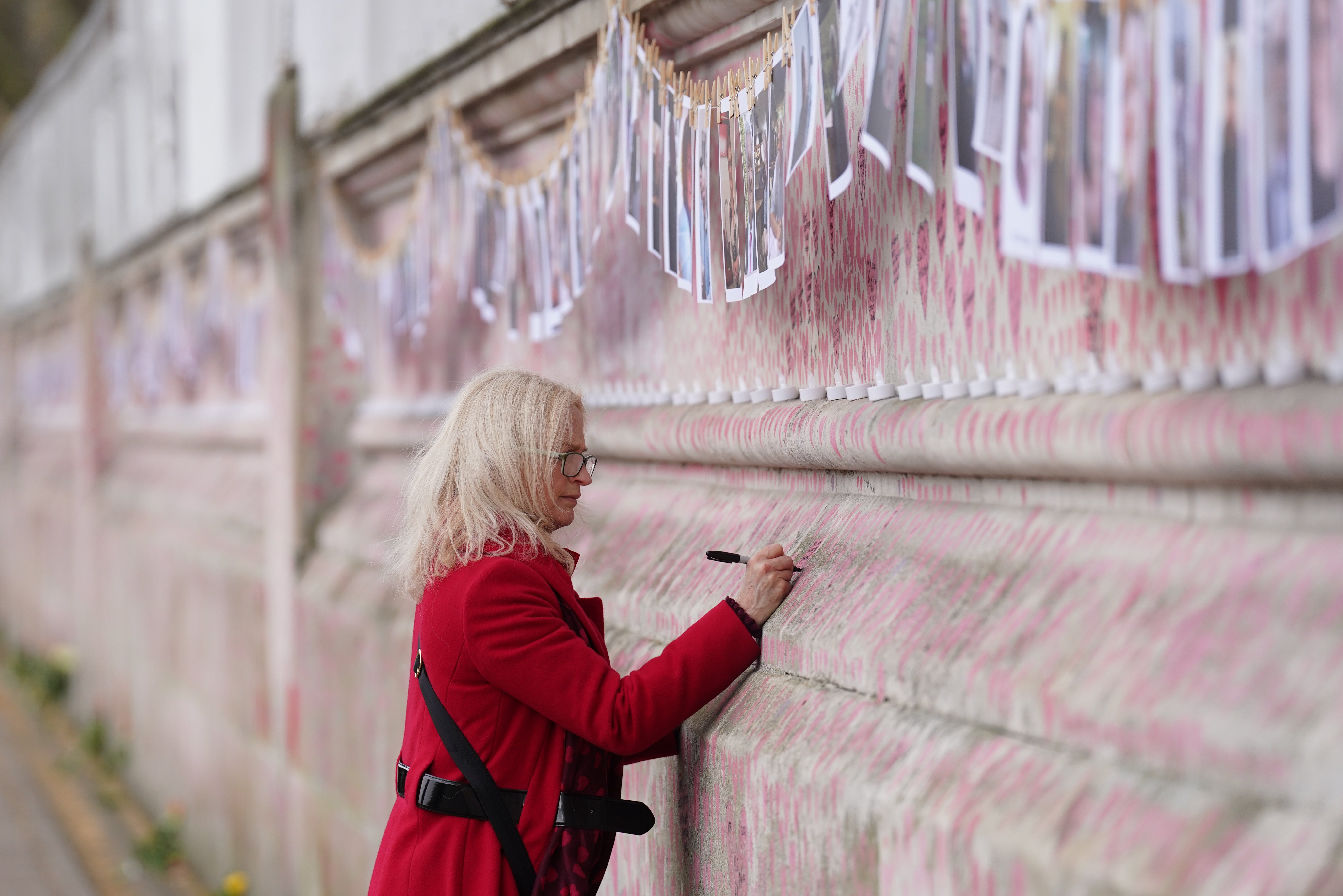 A person leaves a message on the Covid memorial wall in central London (Stefan Rousseau/PA)