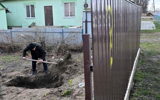 <p>A man exhumes the body of a civilian killed in Andriivka, a village near Kyiv</p>